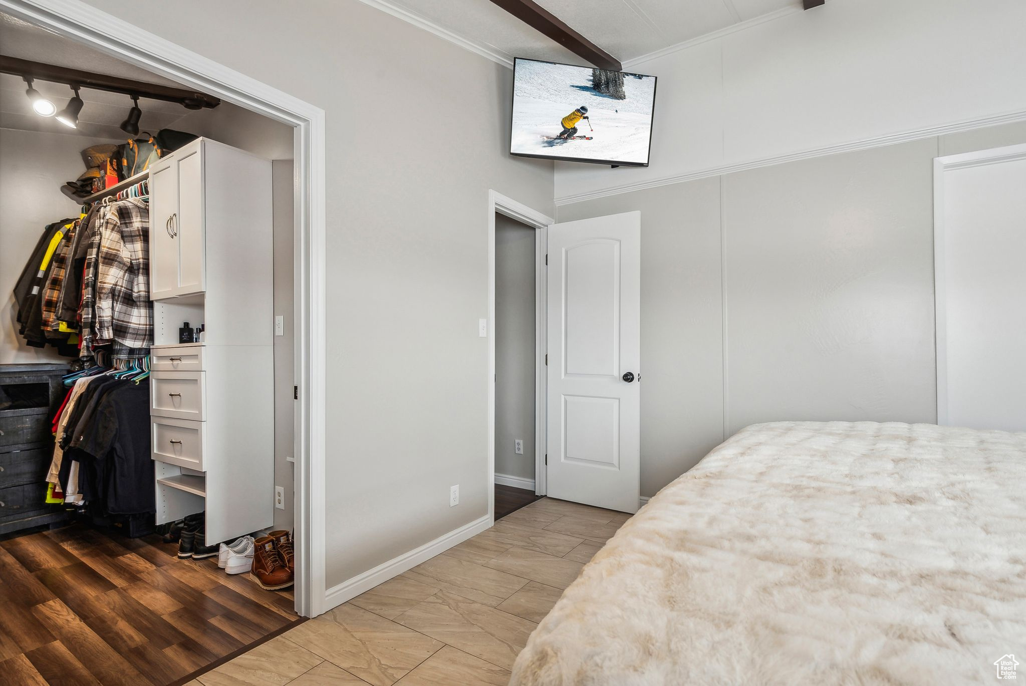 Bedroom featuring baseboards, light wood-style flooring, ornamental molding, a spacious closet, and a closet