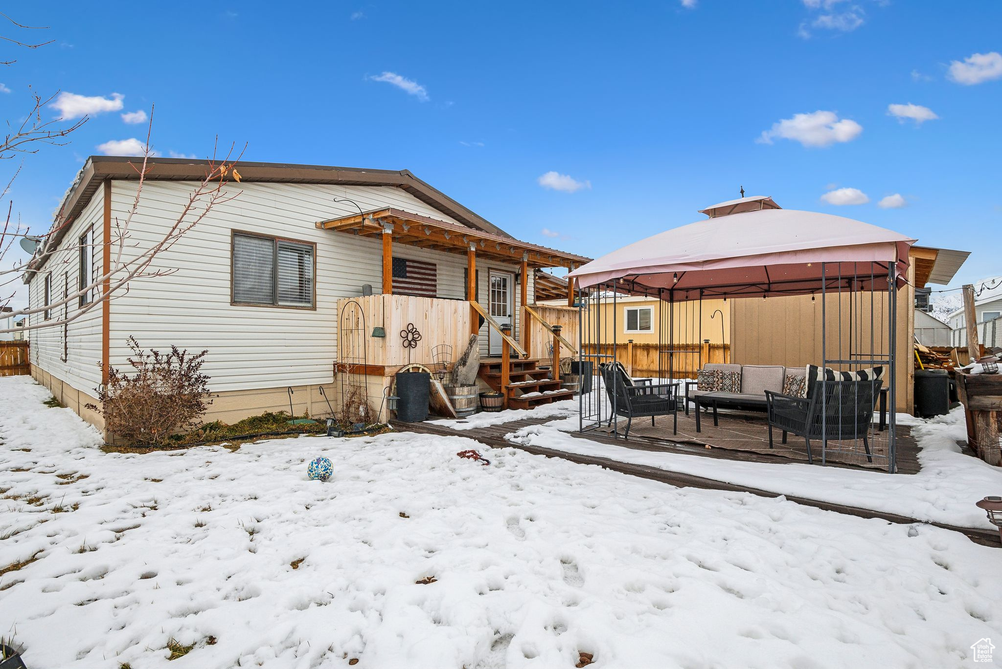 Snow covered house with a gazebo, outdoor lounge area, and fence