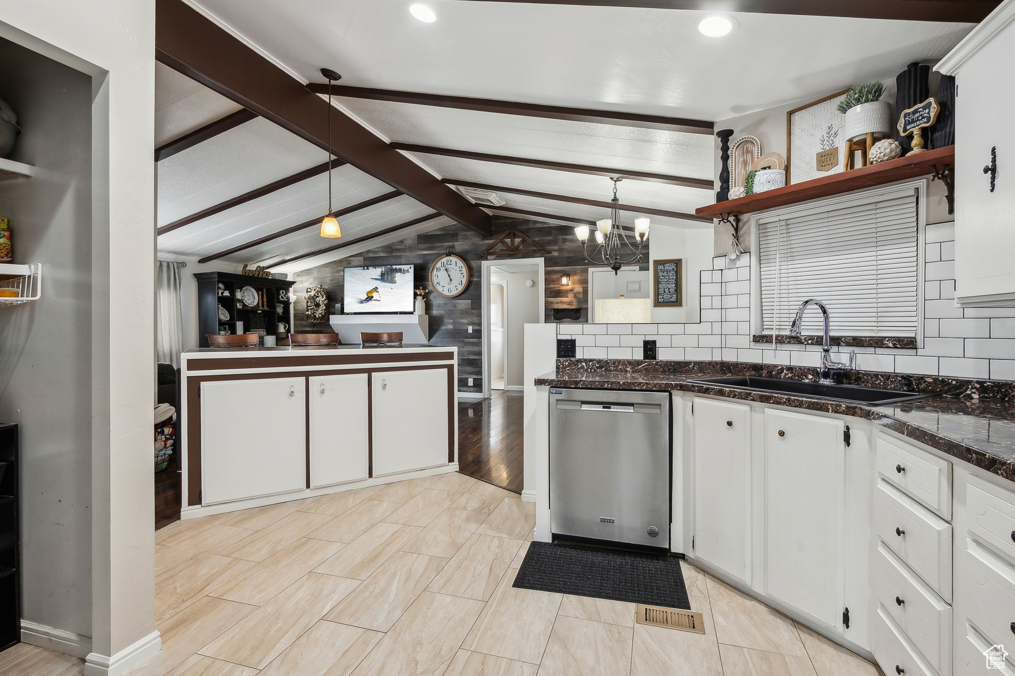 Kitchen with hanging light fixtures, stainless steel dishwasher, and white cabinetry