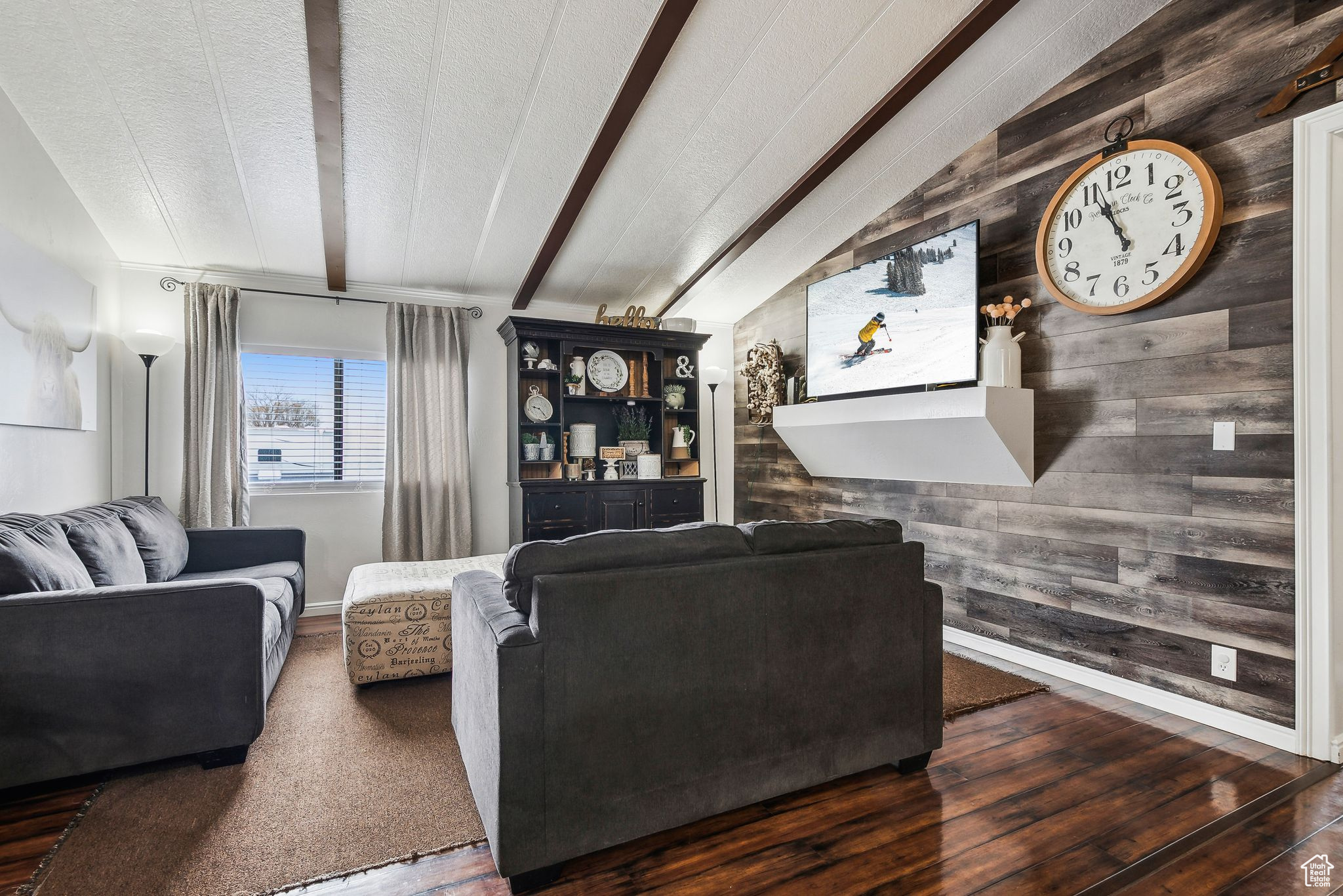 Living room with lofted ceiling with beams, wood walls, a textured ceiling, and wood finished floors