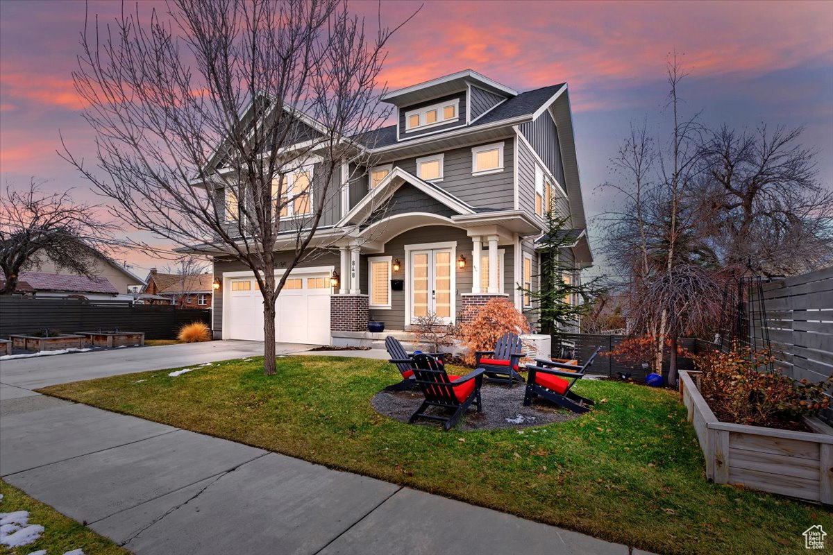 View of front facade with driveway, an attached garage, and a front lawn