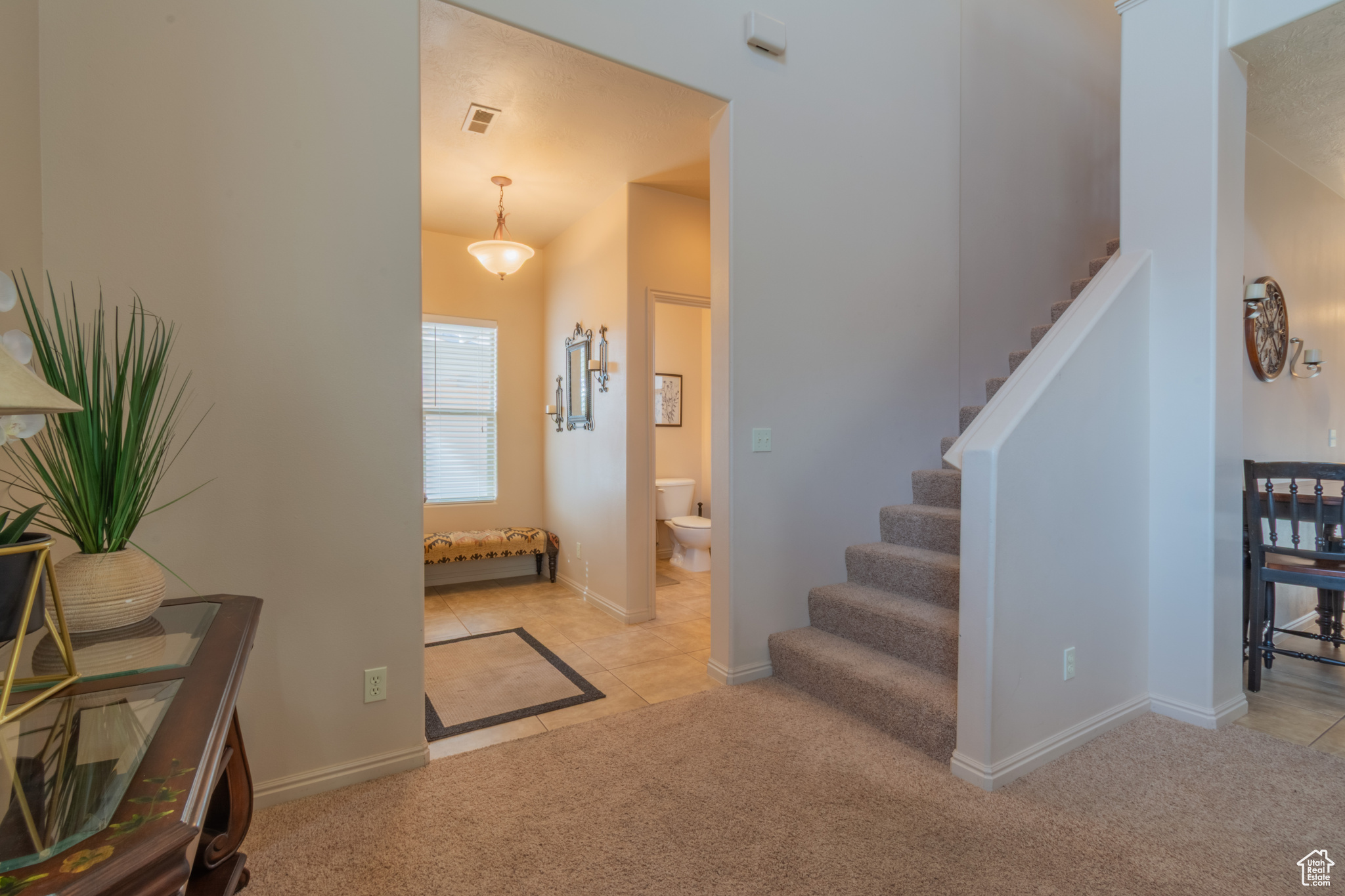 Entrance foyer featuring light tile patterned floors, visible vents, stairway, light carpet, and baseboards