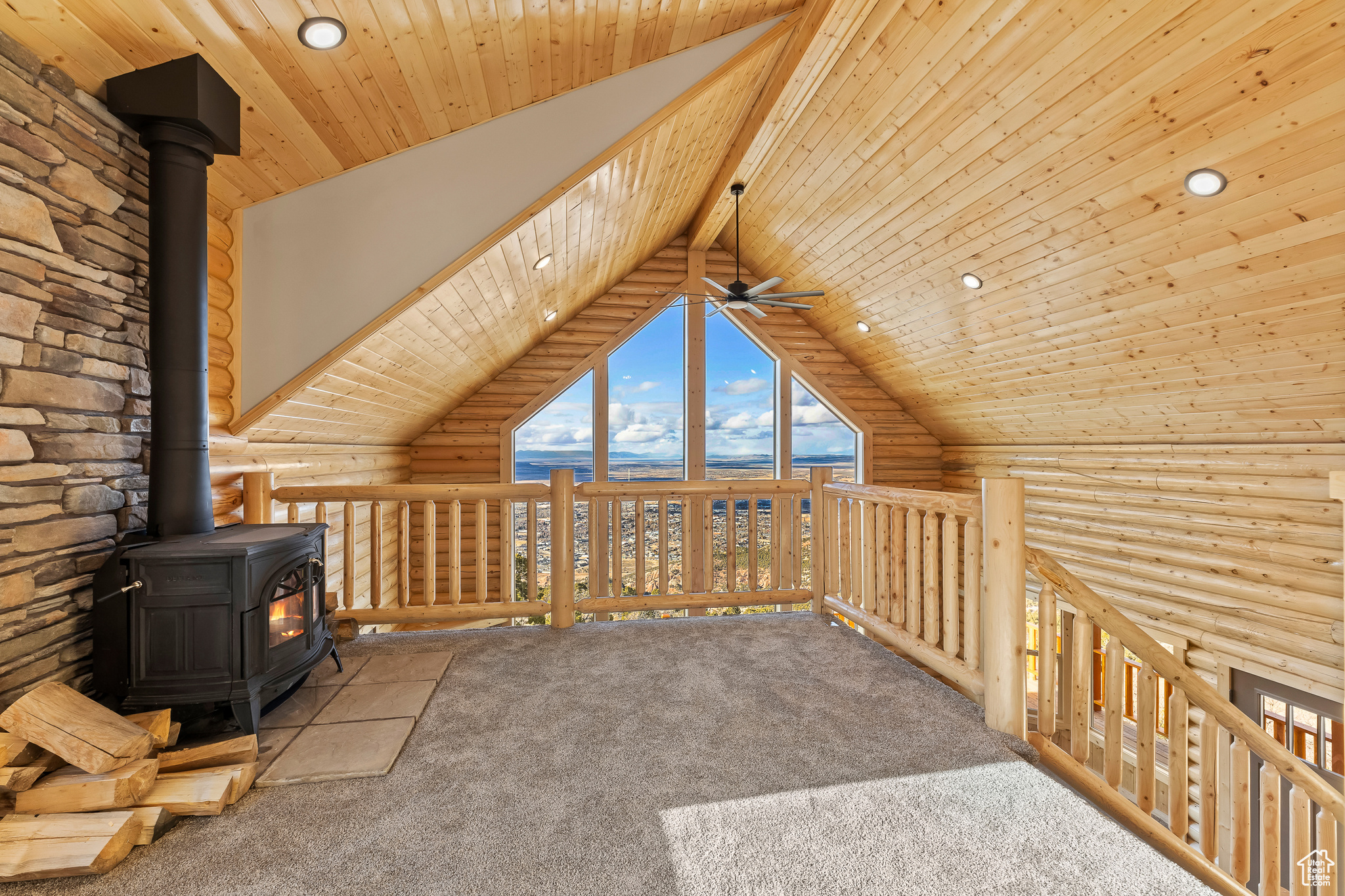 Unfurnished living room with lofted ceiling with beams, wood ceiling, rustic walls, and a wood stove