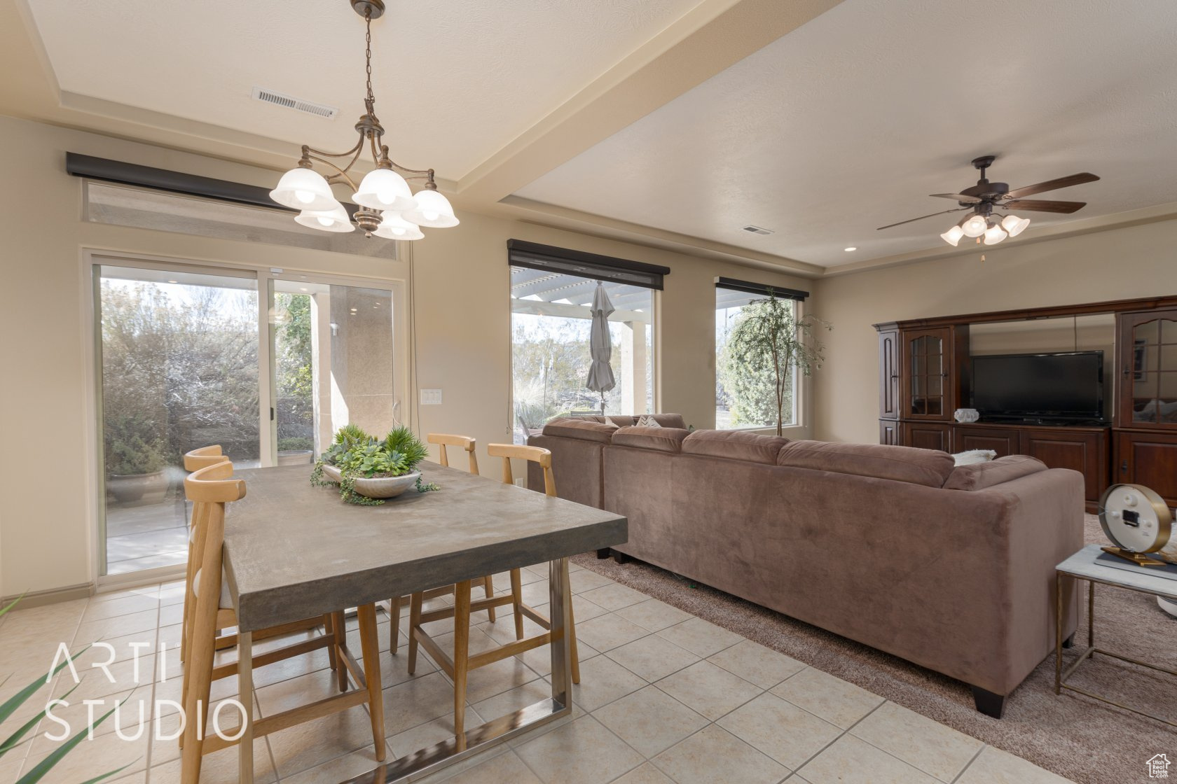 Dining space featuring ceiling fan with notable chandelier and light tile patterned floors