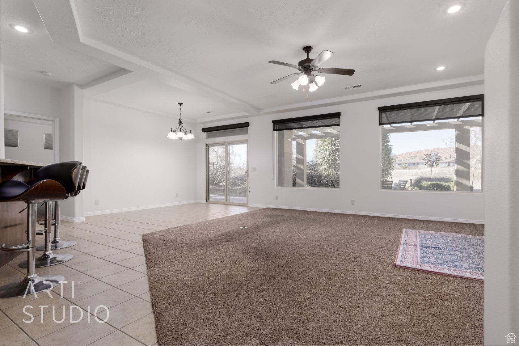 Tiled living room featuring ceiling fan with notable chandelier