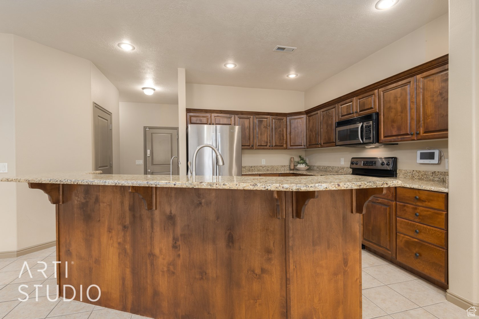 Kitchen featuring a large island, light tile patterned floors, and appliances with stainless steel finishes