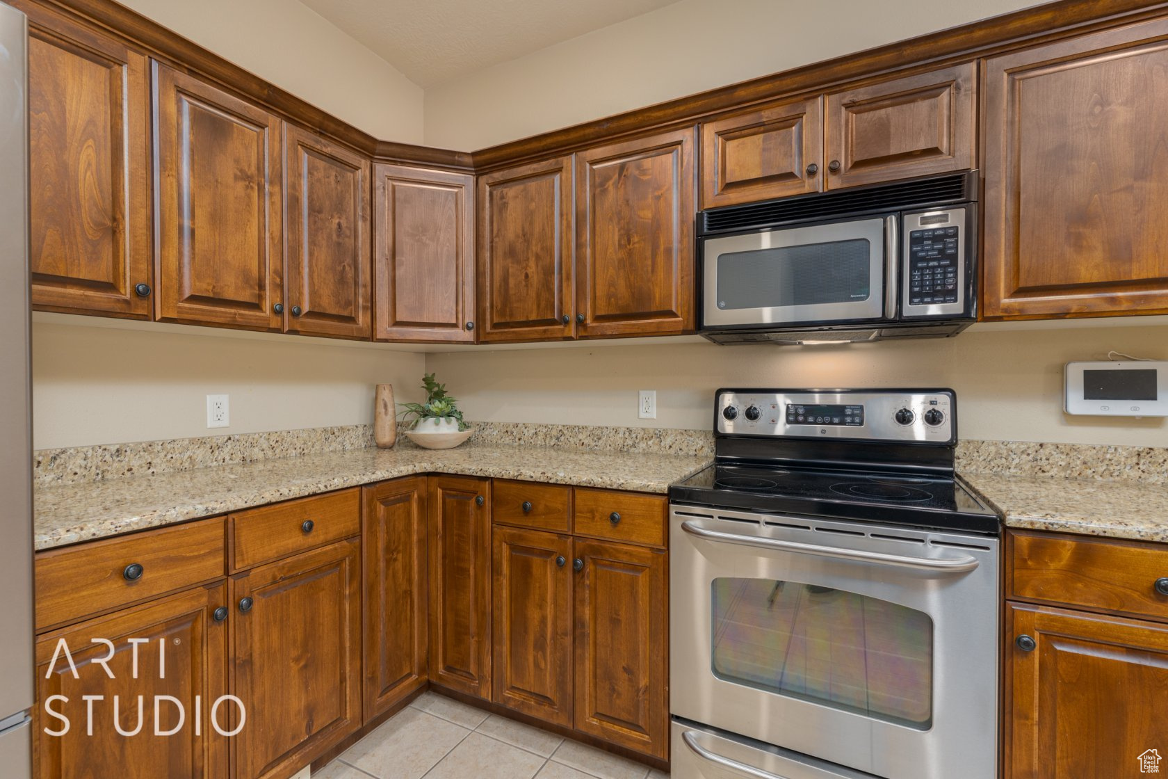 Kitchen with light stone counters, light tile patterned floors, and stainless steel appliances