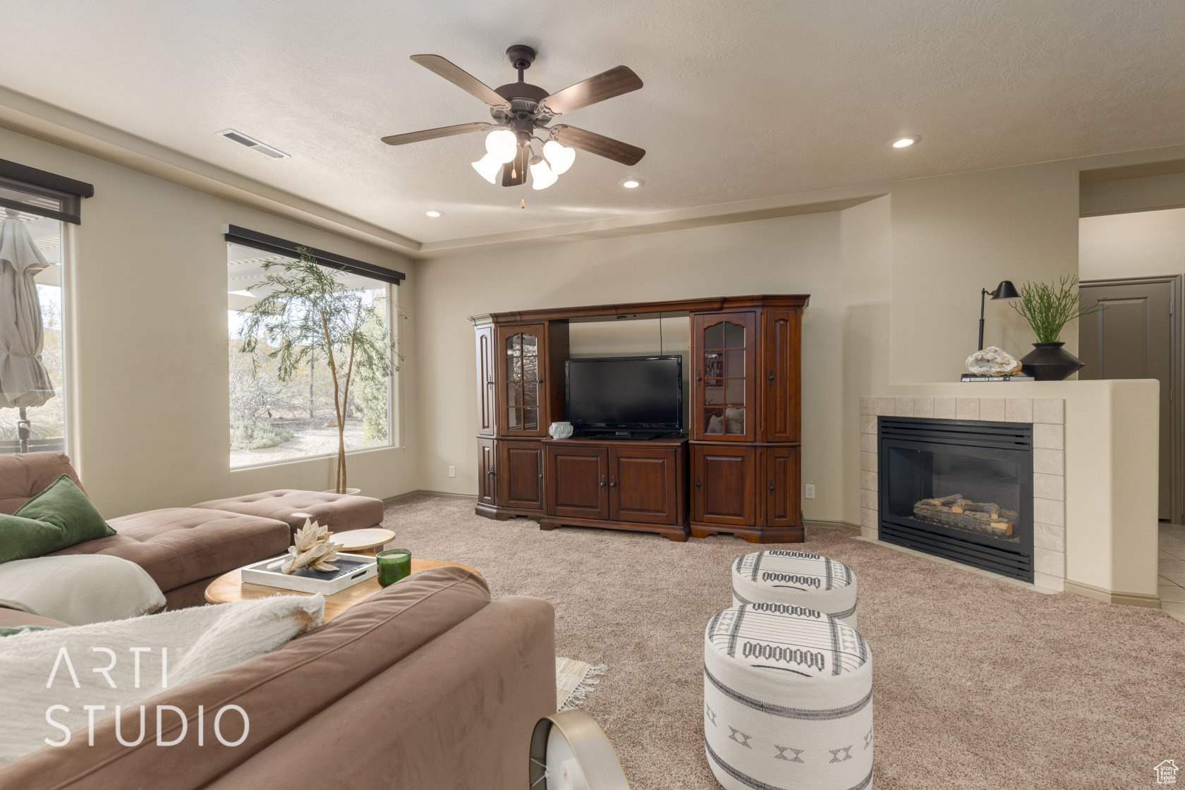 Living room with ceiling fan, a tiled fireplace, and light carpet