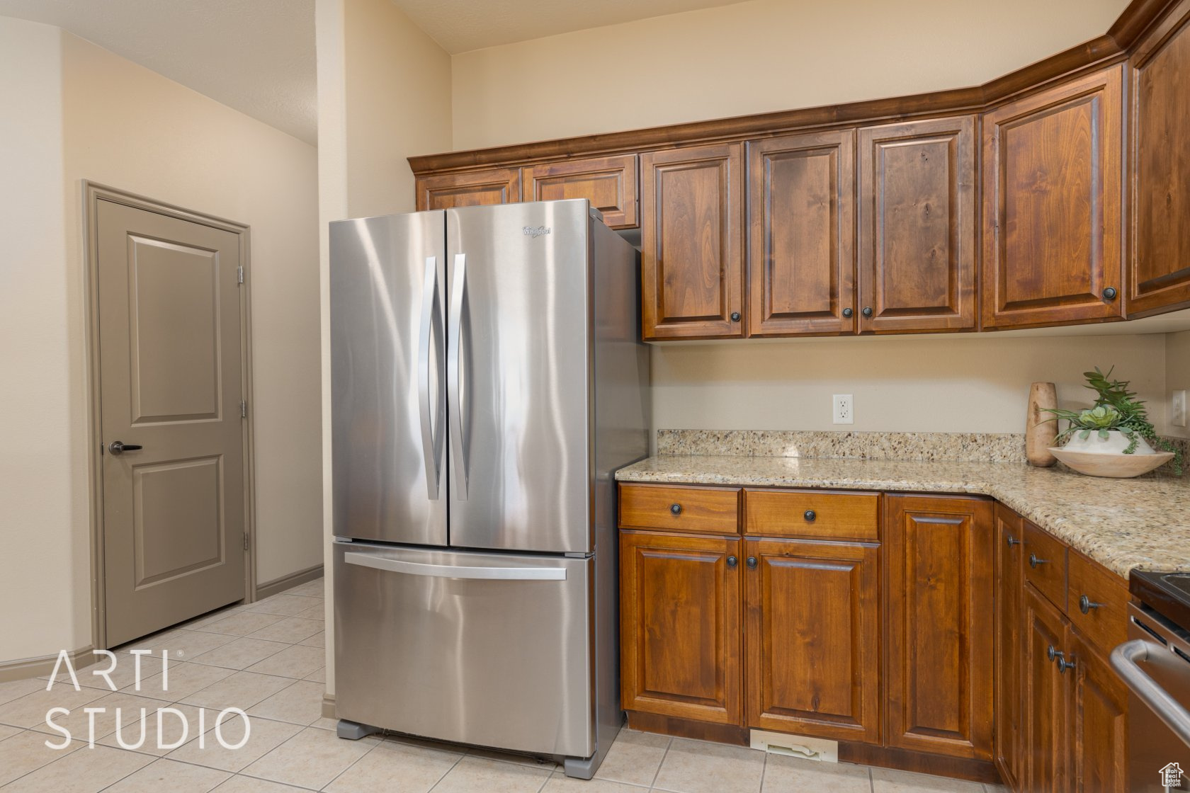 Kitchen with appliances with stainless steel finishes, light tile patterned floors, and light stone counters