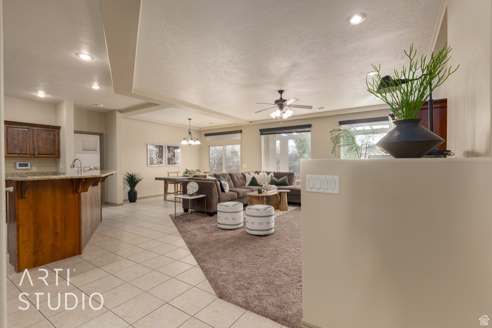 Tiled living room featuring ceiling fan with notable chandelier, a wealth of natural light, and a textured ceiling
