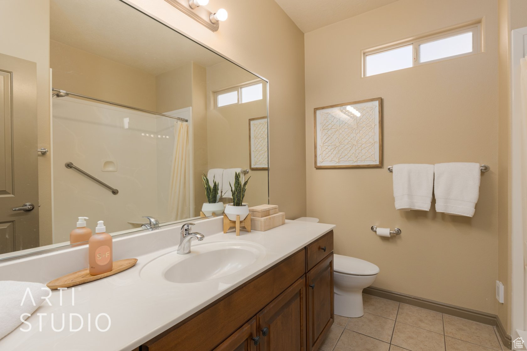 Bathroom featuring tile patterned floors, plenty of natural light, curtained shower, and vanity