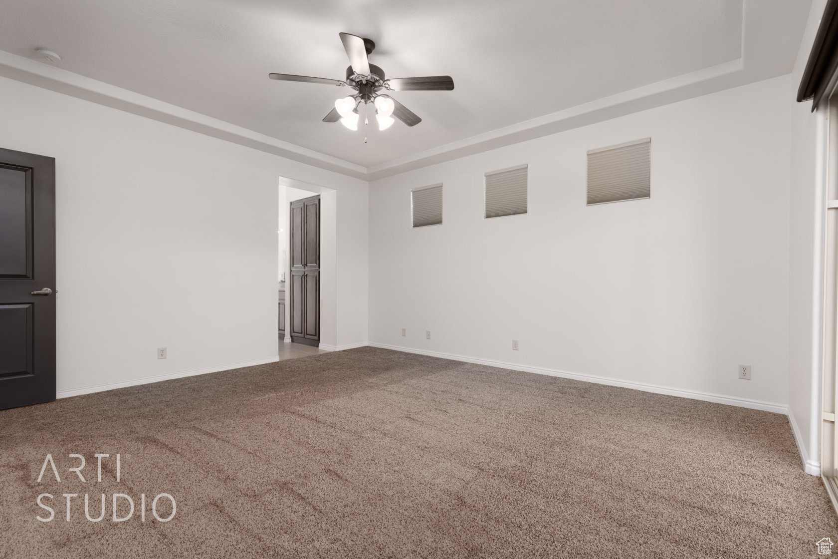 Carpeted spare room featuring ceiling fan and a tray ceiling