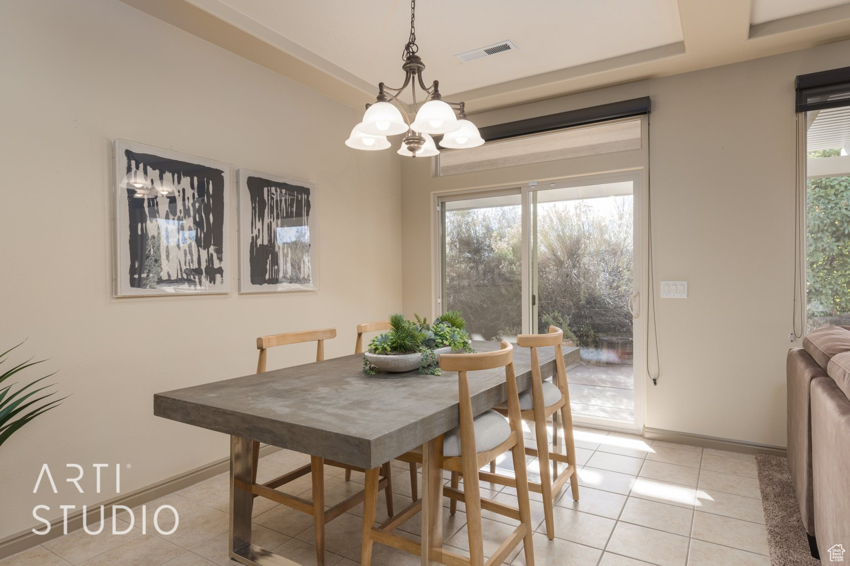 Tiled dining room featuring an inviting chandelier and a tray ceiling