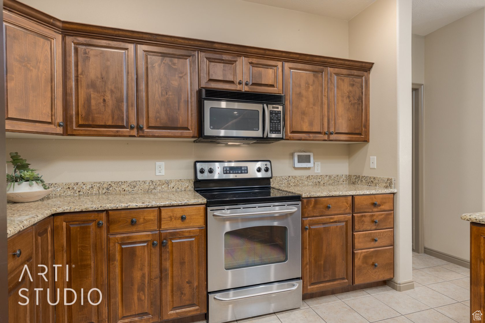 Kitchen with light stone counters, appliances with stainless steel finishes, and light tile patterned floors