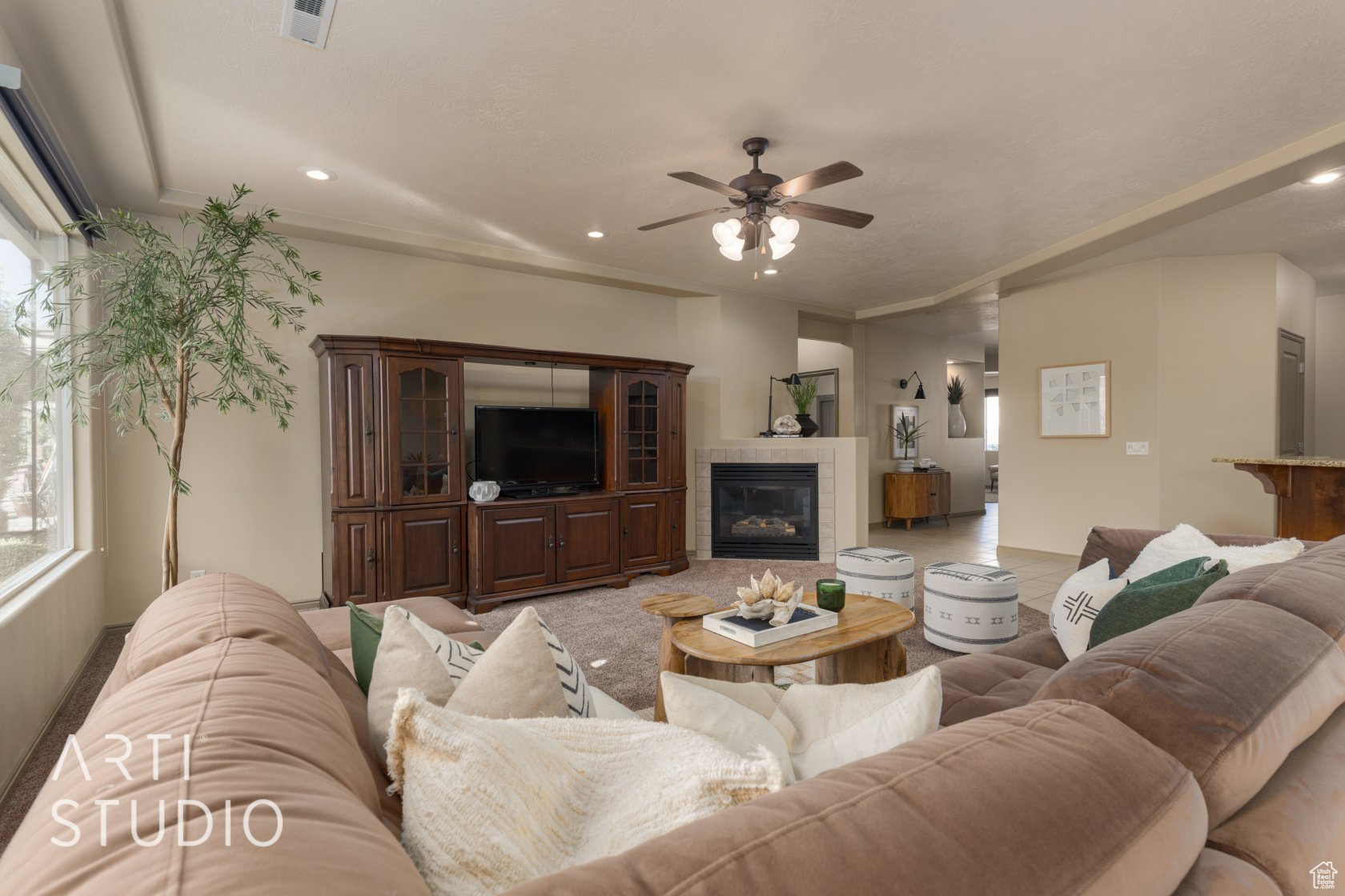 Living room featuring a tile fireplace, ornamental molding, and ceiling fan