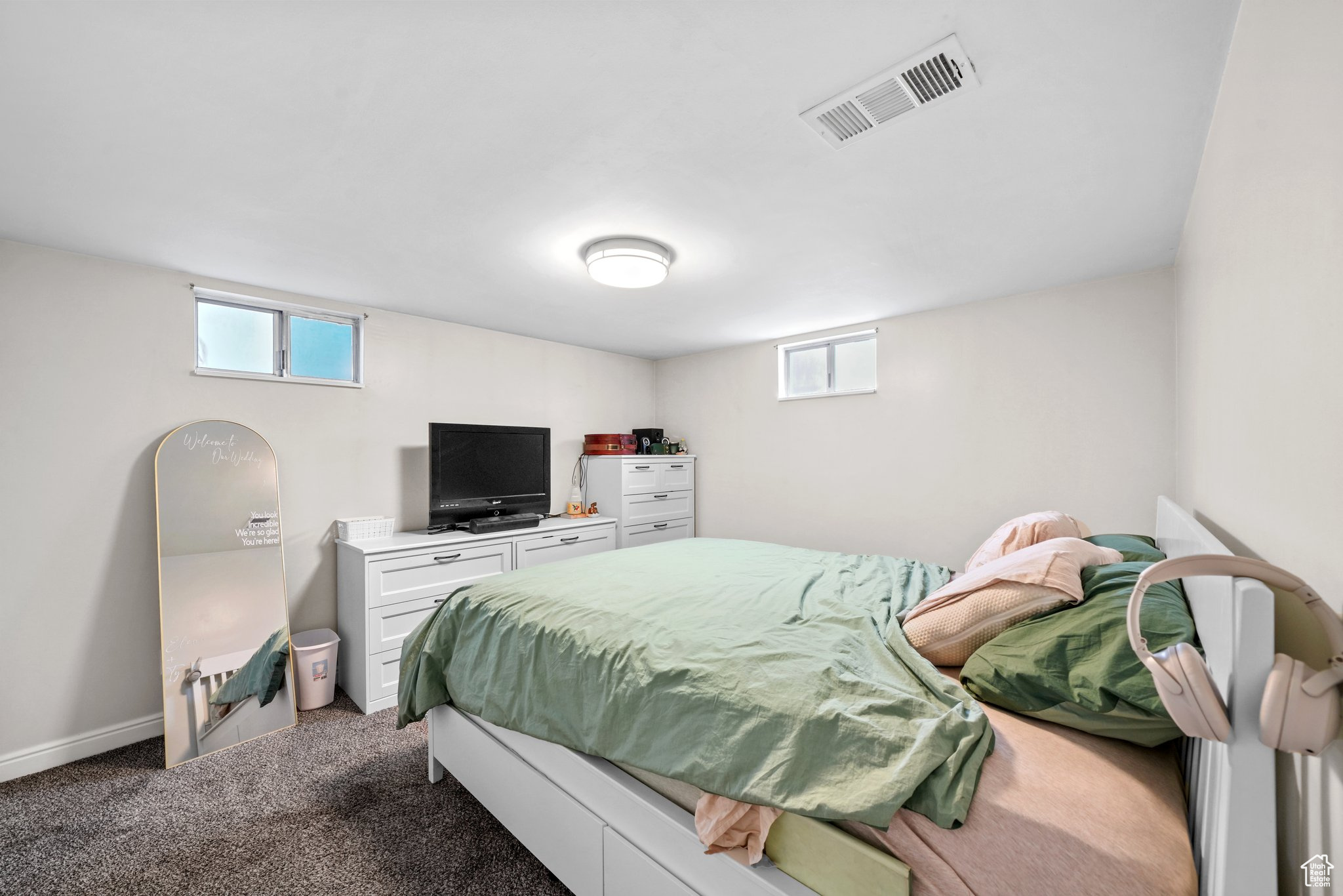 Bedroom featuring dark colored carpet, visible vents, and baseboards