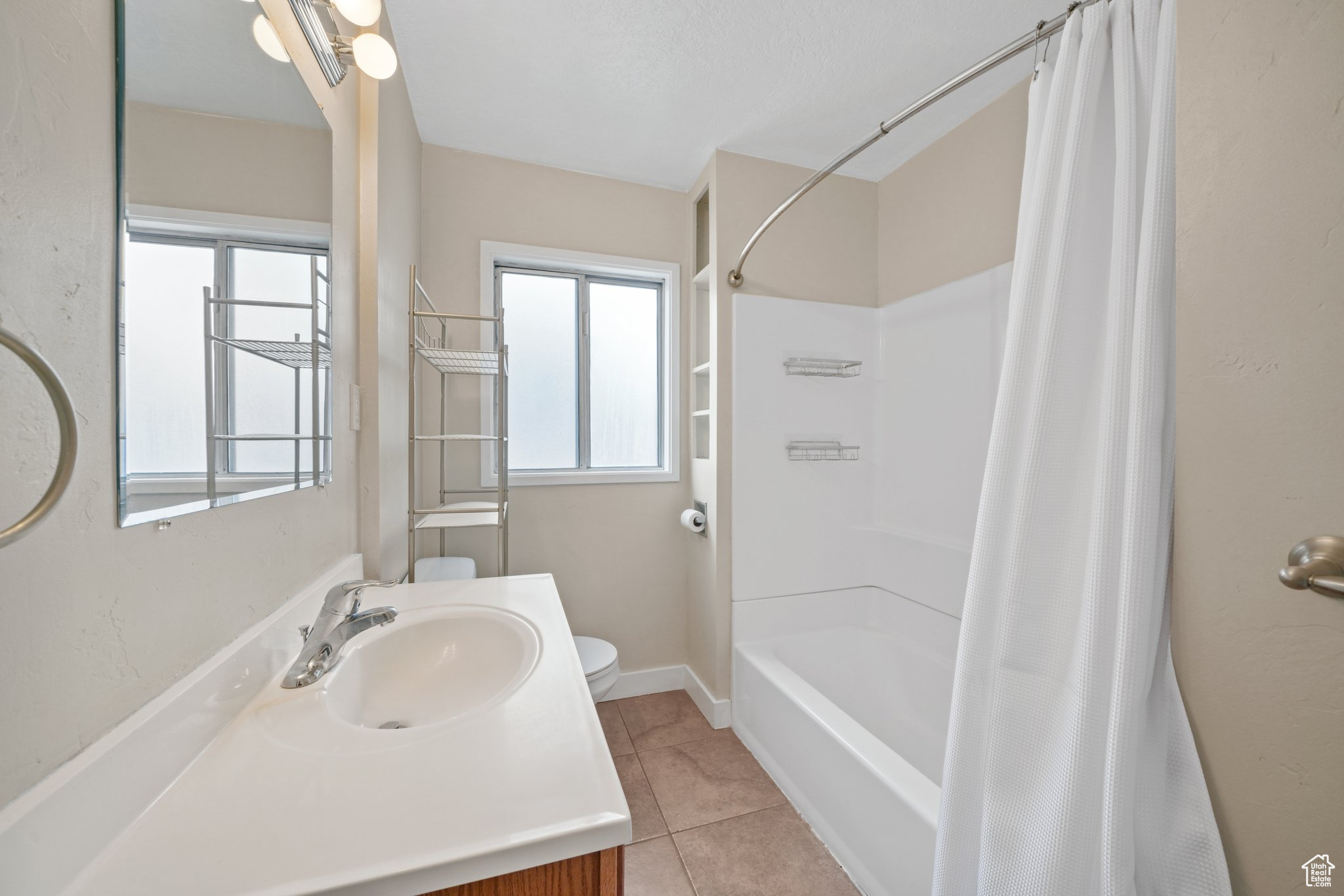 Bathroom featuring a wealth of natural light, tile patterned flooring, vanity, and toilet