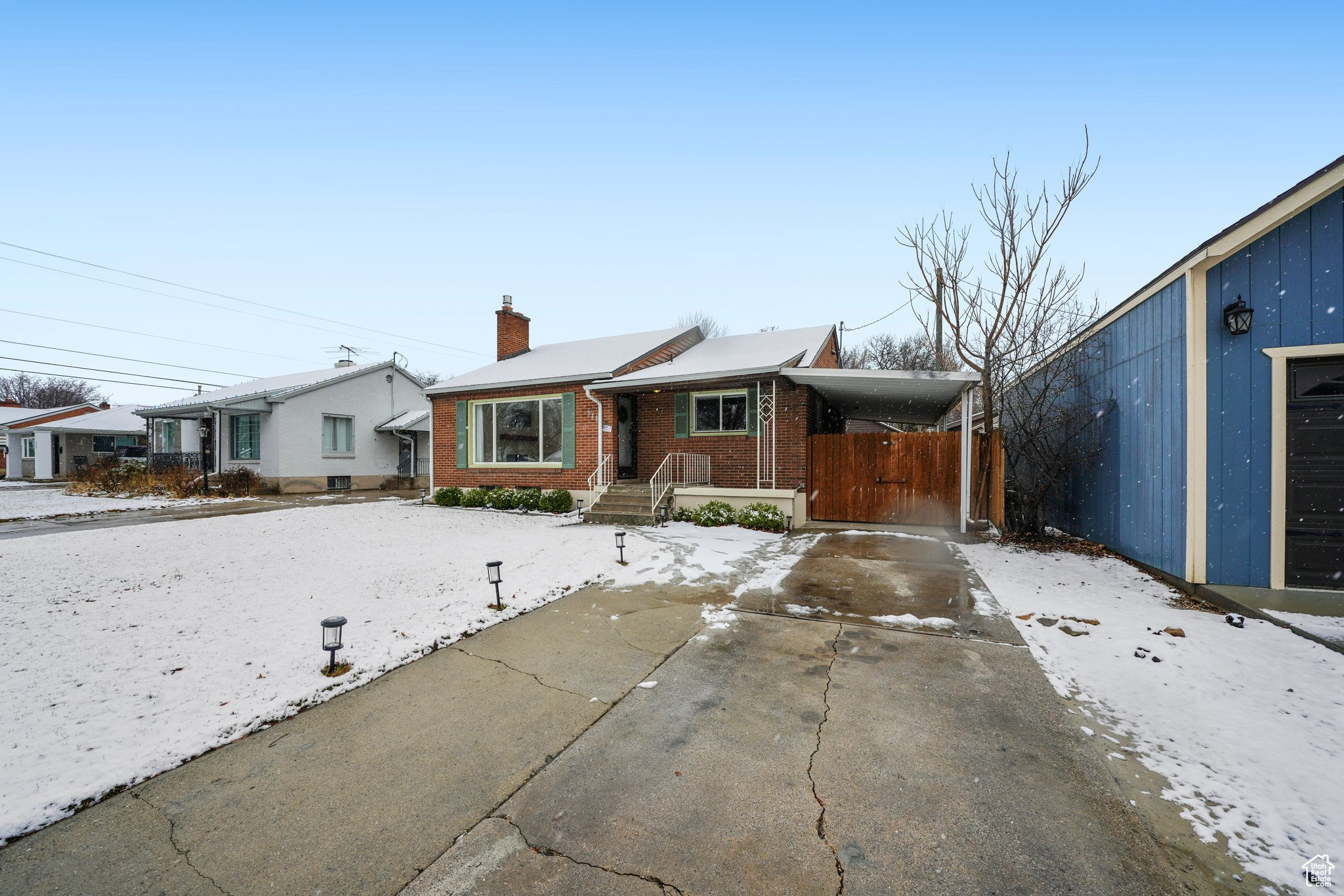 View of front of home with driveway, brick siding, a chimney, and an attached carport