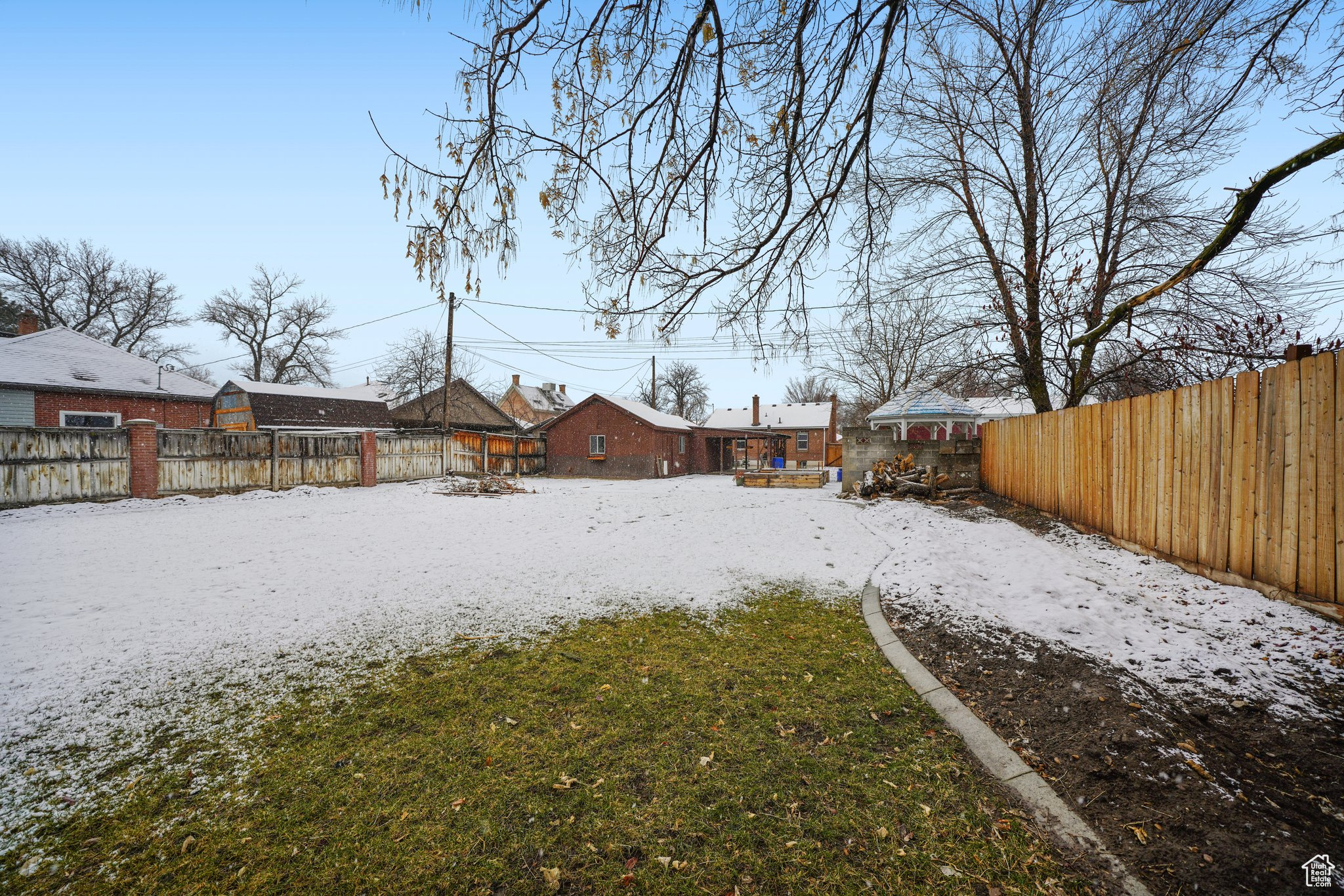 Snowy yard featuring a fenced backyard and a residential view