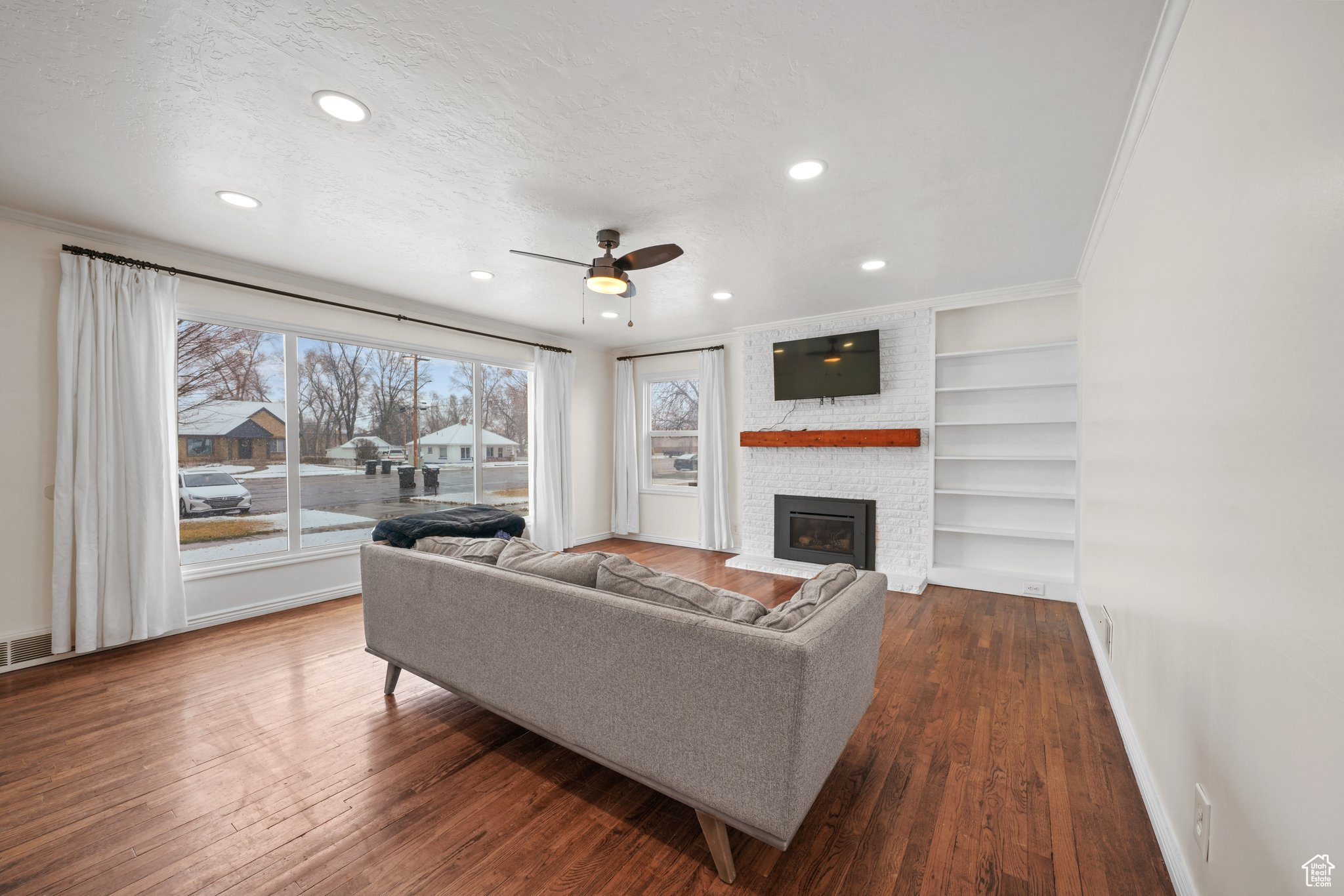 Living room featuring a textured ceiling, built in shelves, dark wood finished floors, and baseboards