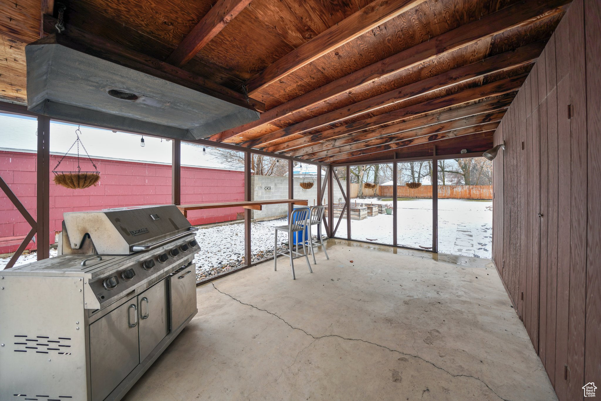 Snow covered patio featuring a fenced backyard and area for grilling