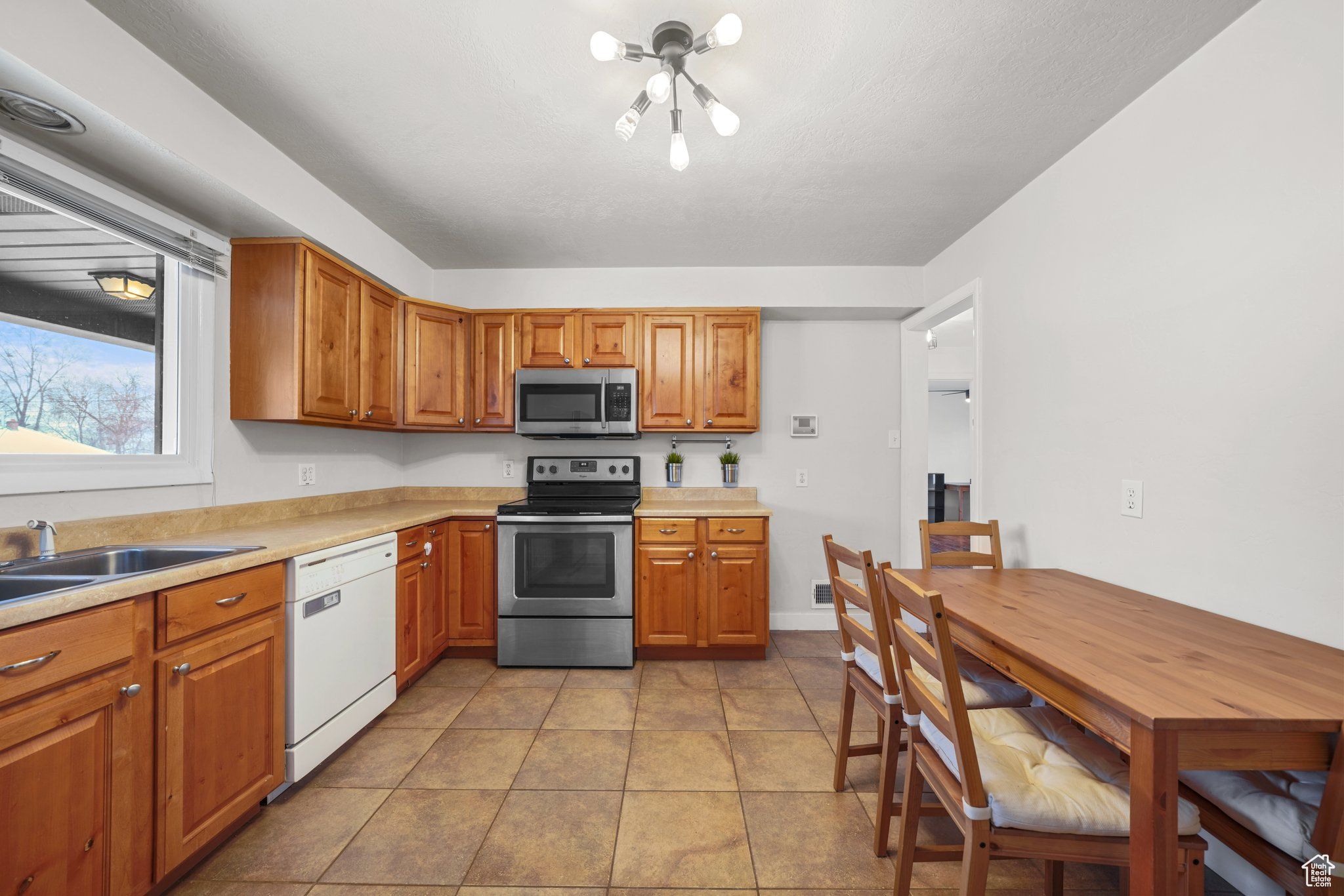 Kitchen featuring stainless steel appliances, brown cabinetry, and light countertops