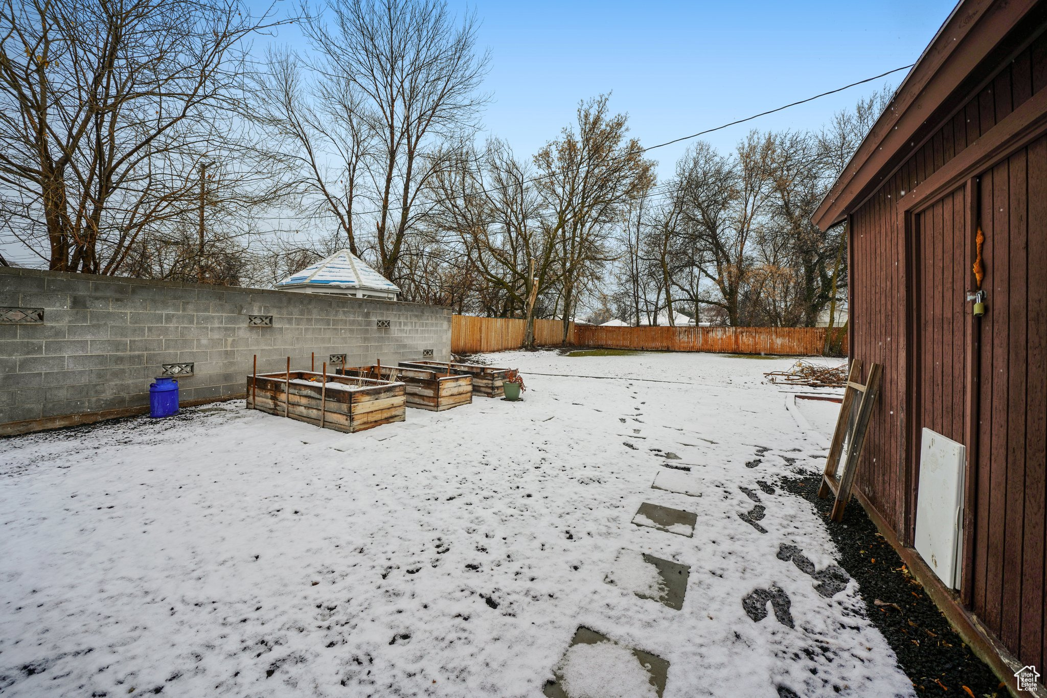 Yard layered in snow featuring a fenced backyard and a vegetable garden