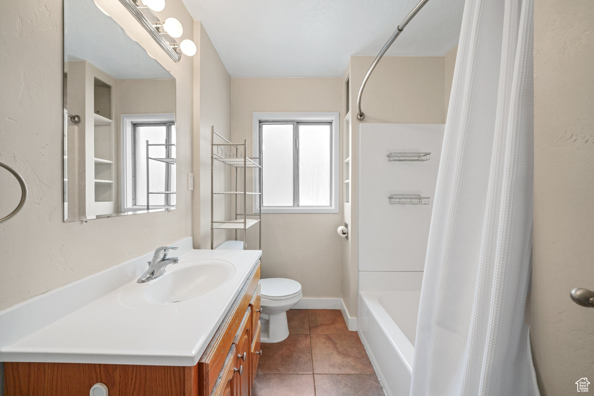 Full bathroom with shower / bath combo, baseboards, toilet, tile patterned flooring, and vanity
