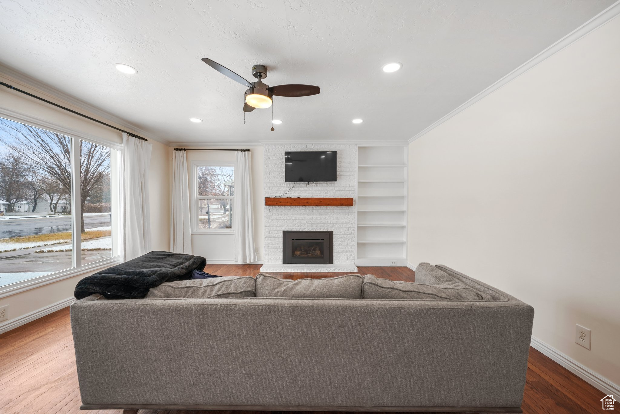 Living area featuring built in features, a fireplace, ornamental molding, wood finished floors, and baseboards