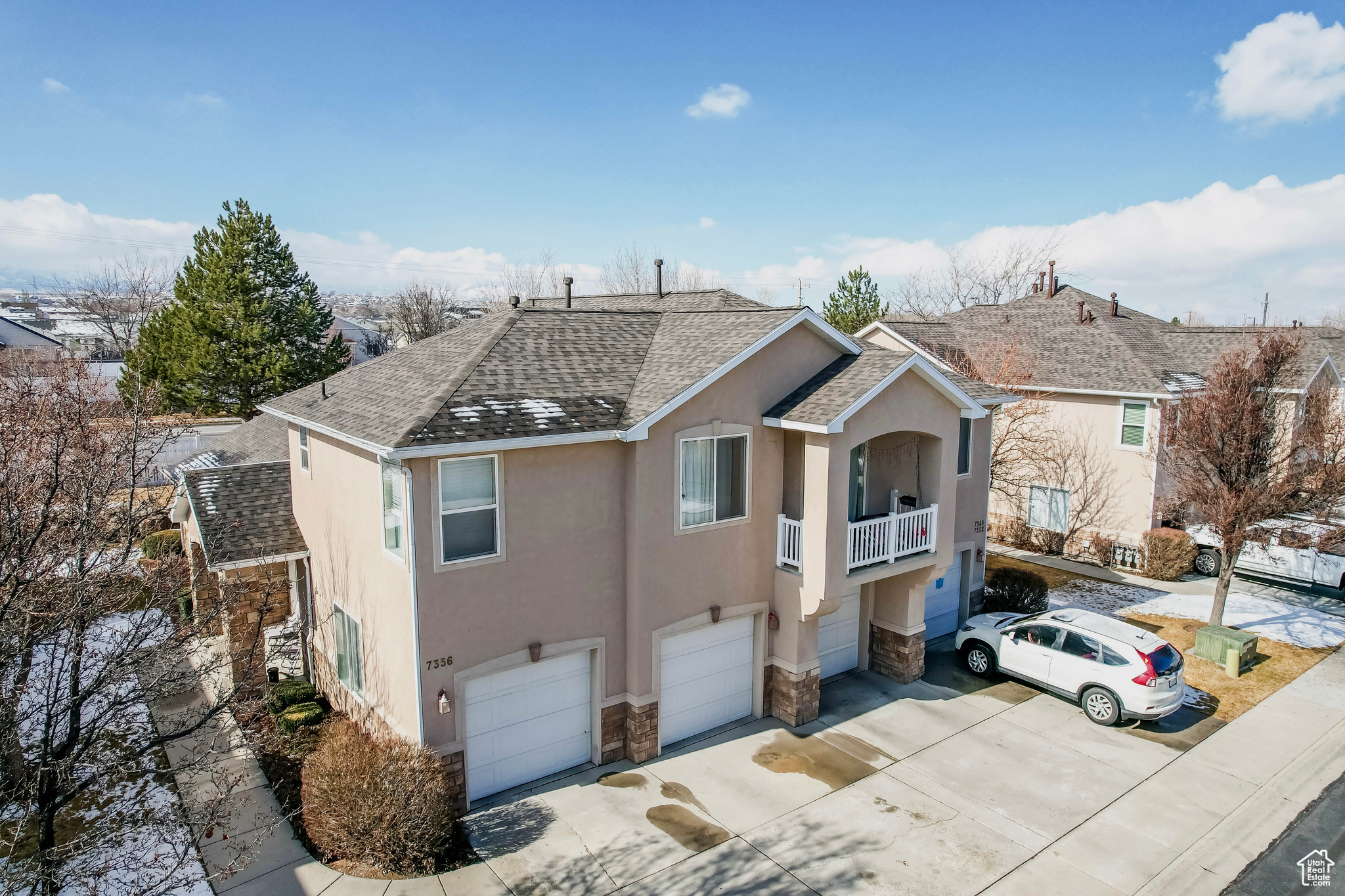 View of front of property featuring driveway, a garage, a shingled roof, stone siding, and stucco siding