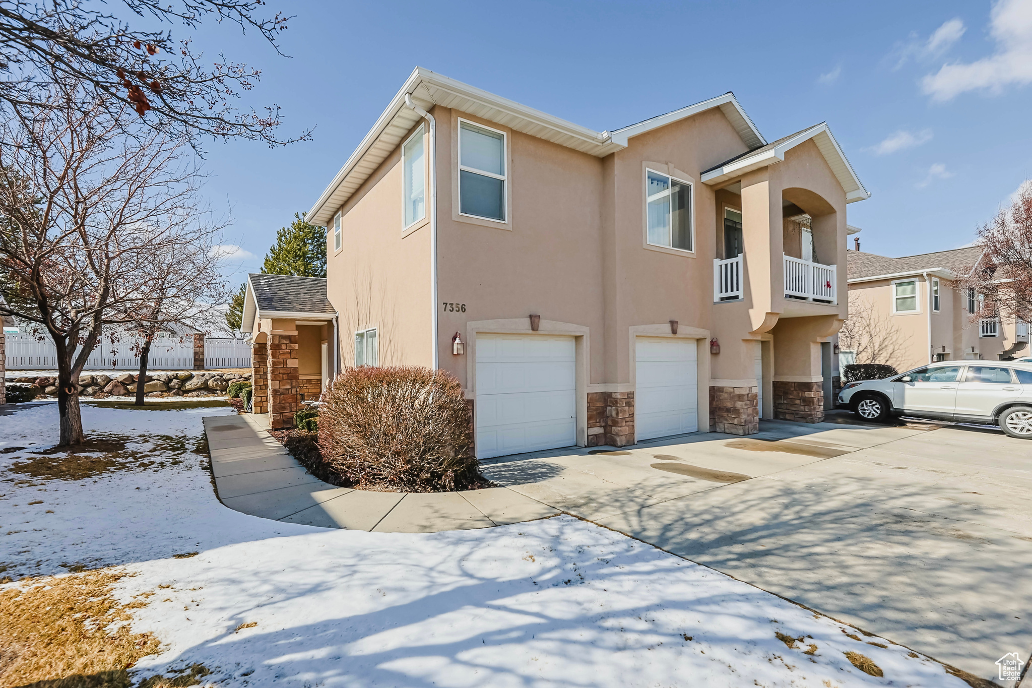 Multi unit property featuring stone siding, an attached garage, driveway, and stucco siding