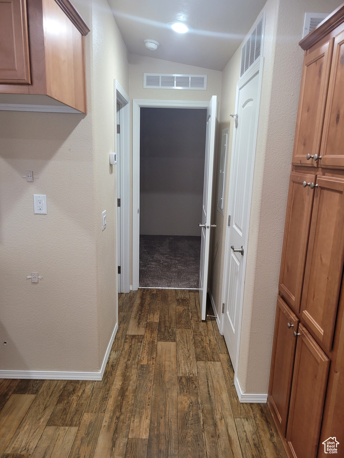 Hall featuring dark wood-type flooring, visible vents, and baseboards