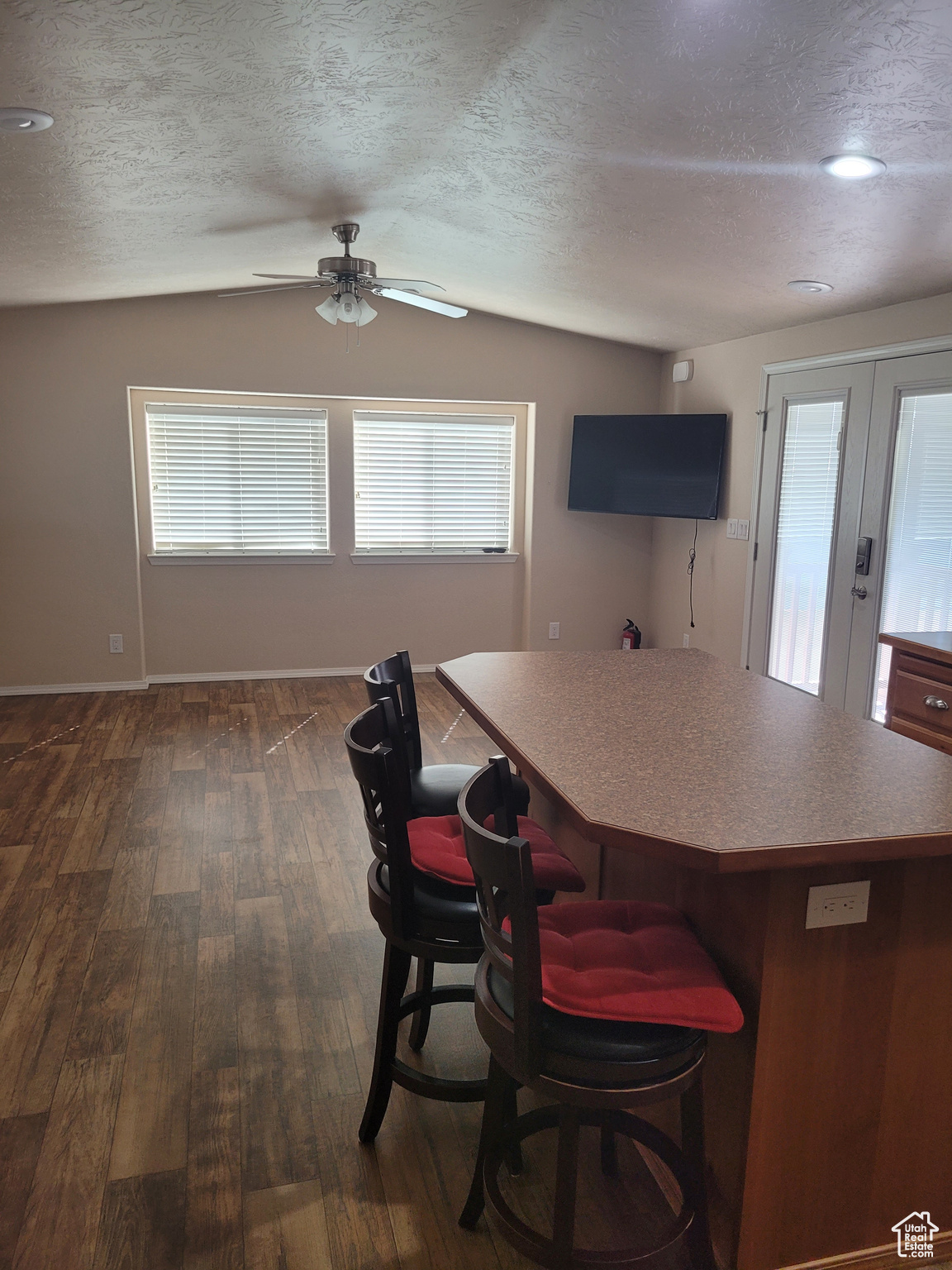 Kitchen with lofted ceiling, a textured ceiling, dark wood-style flooring, and a center island