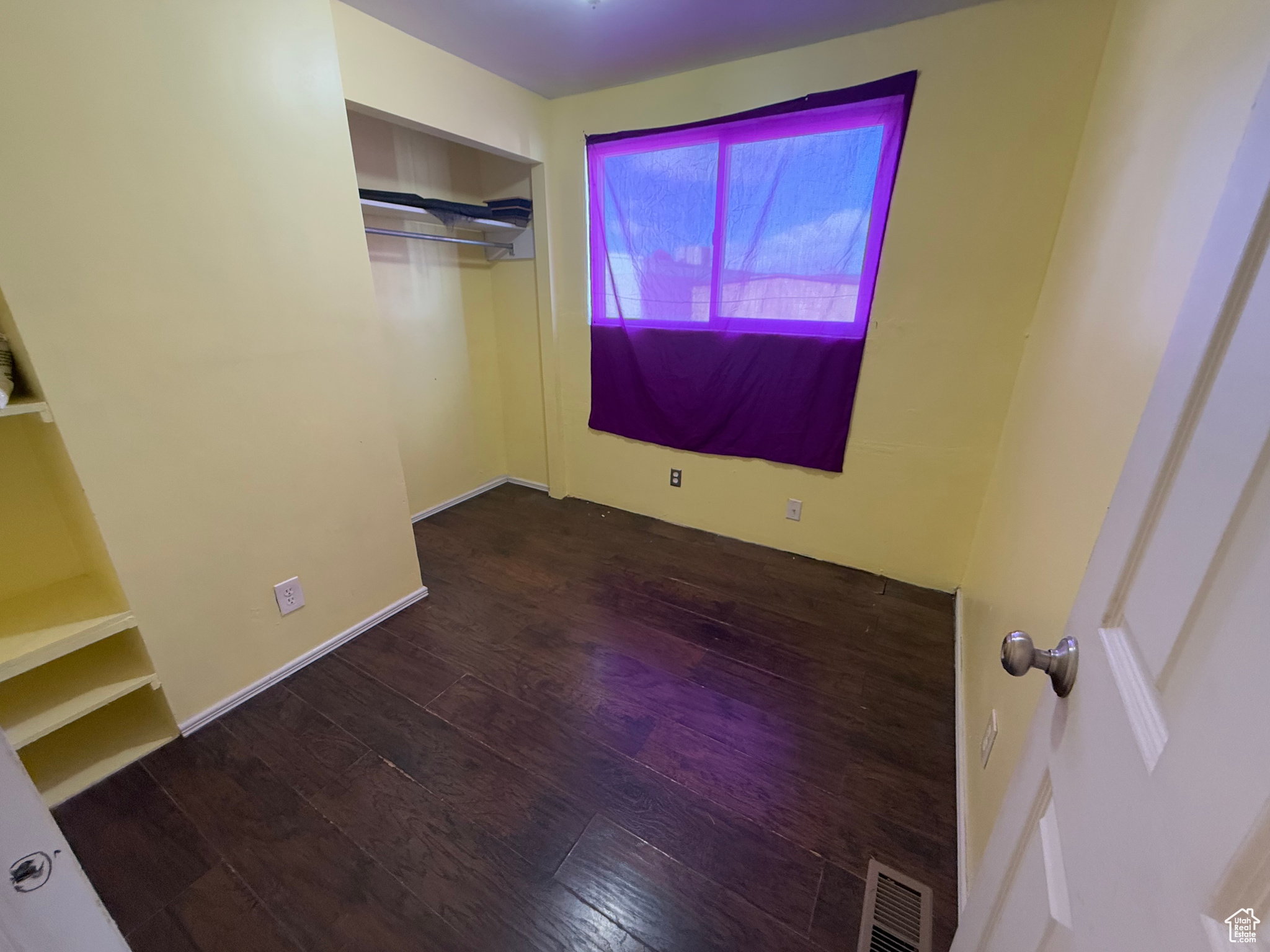 Unfurnished room featuring visible vents and dark wood finished floors