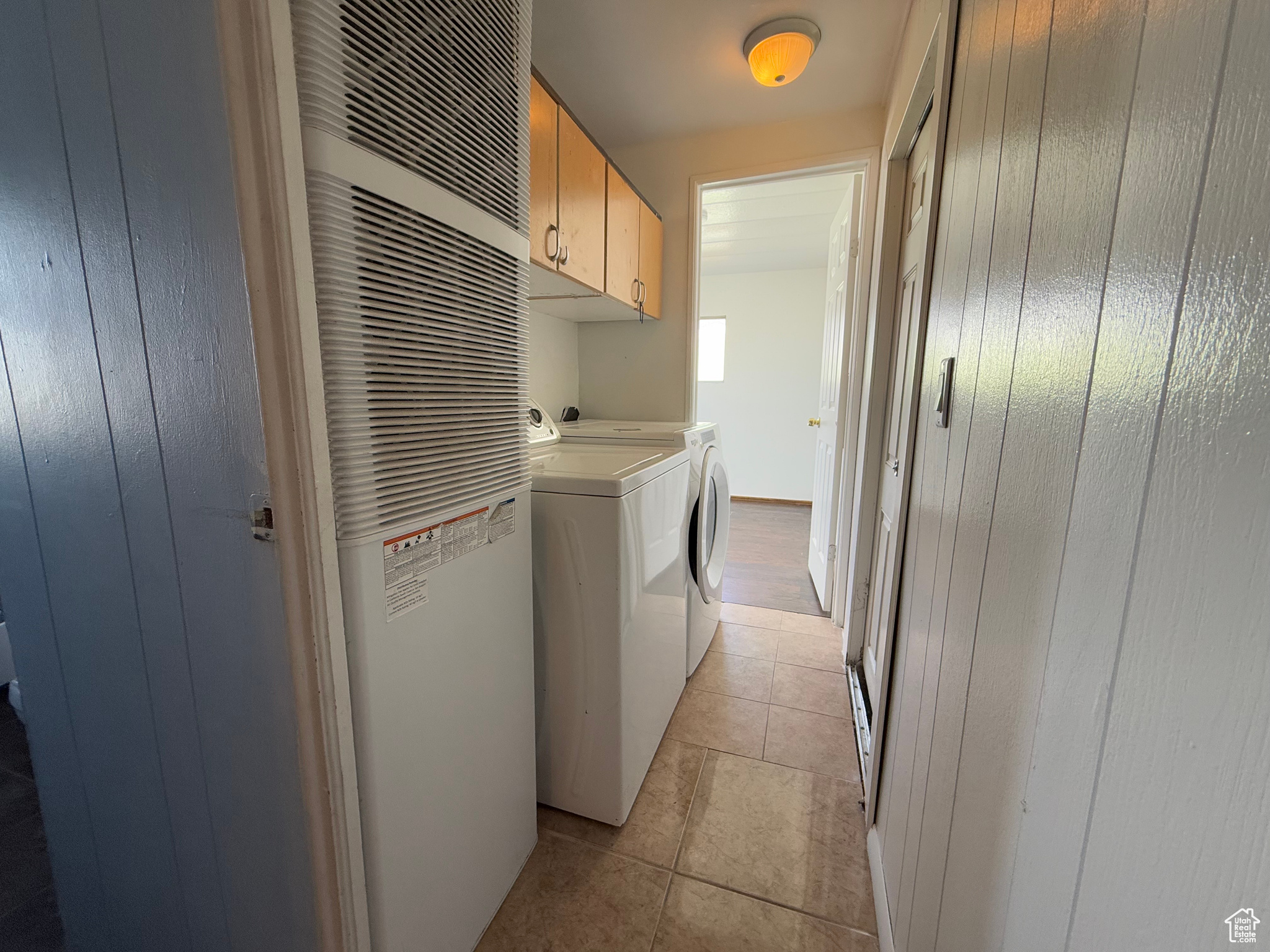 Laundry room featuring a heating unit, cabinet space, independent washer and dryer, and light tile patterned floors