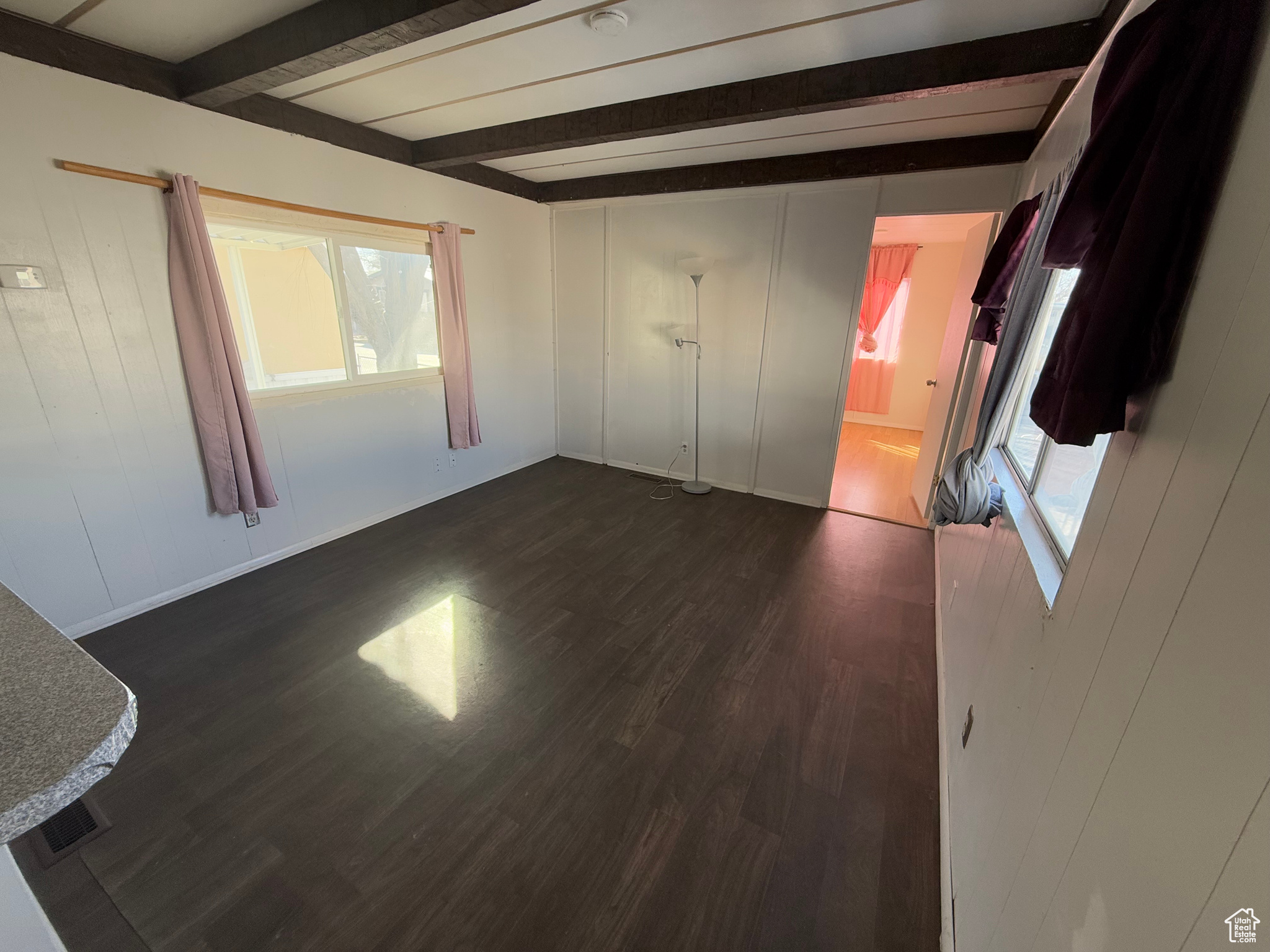 Unfurnished bedroom featuring dark wood finished floors and beamed ceiling