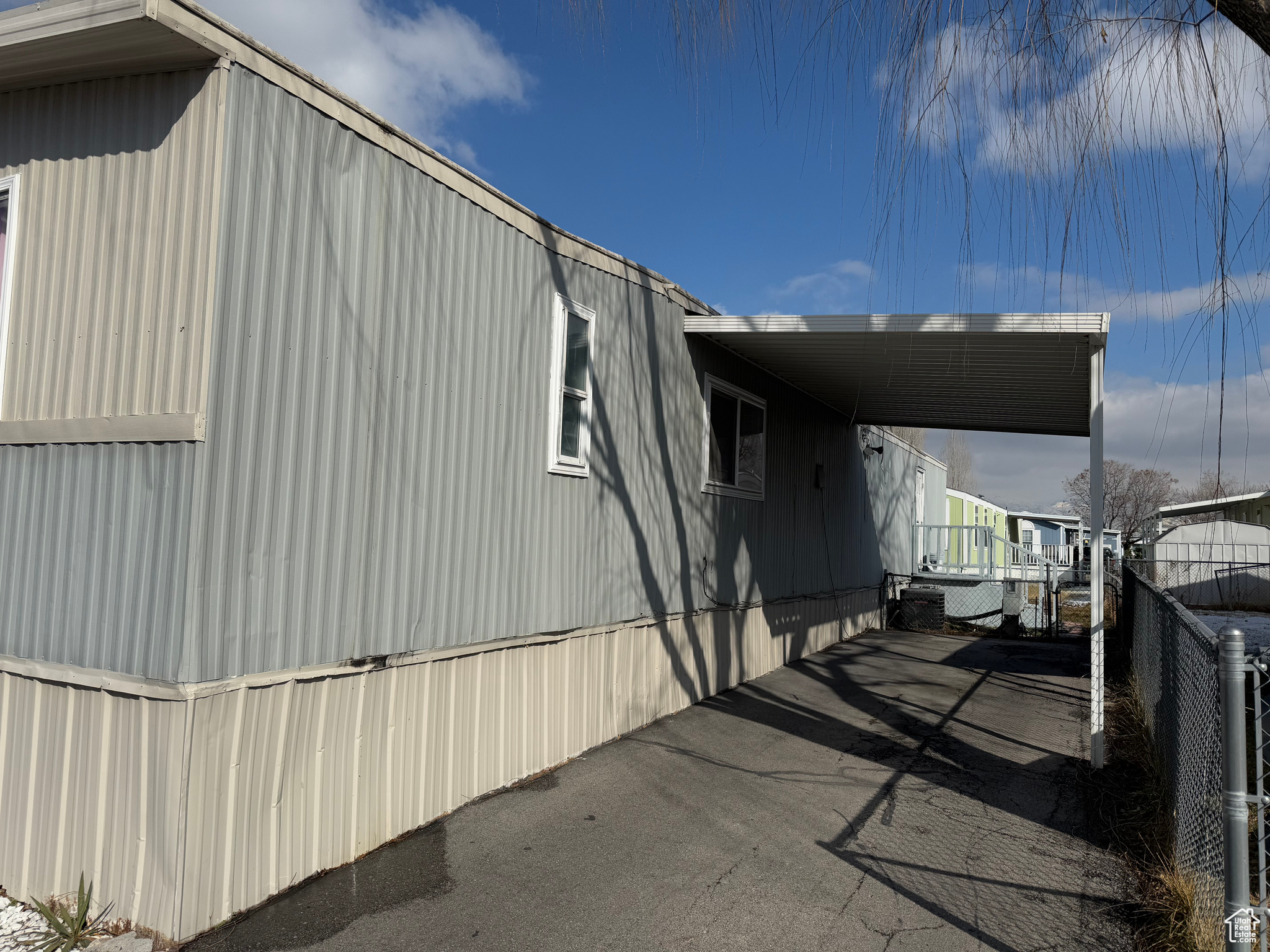 View of side of home with an attached carport and fence
