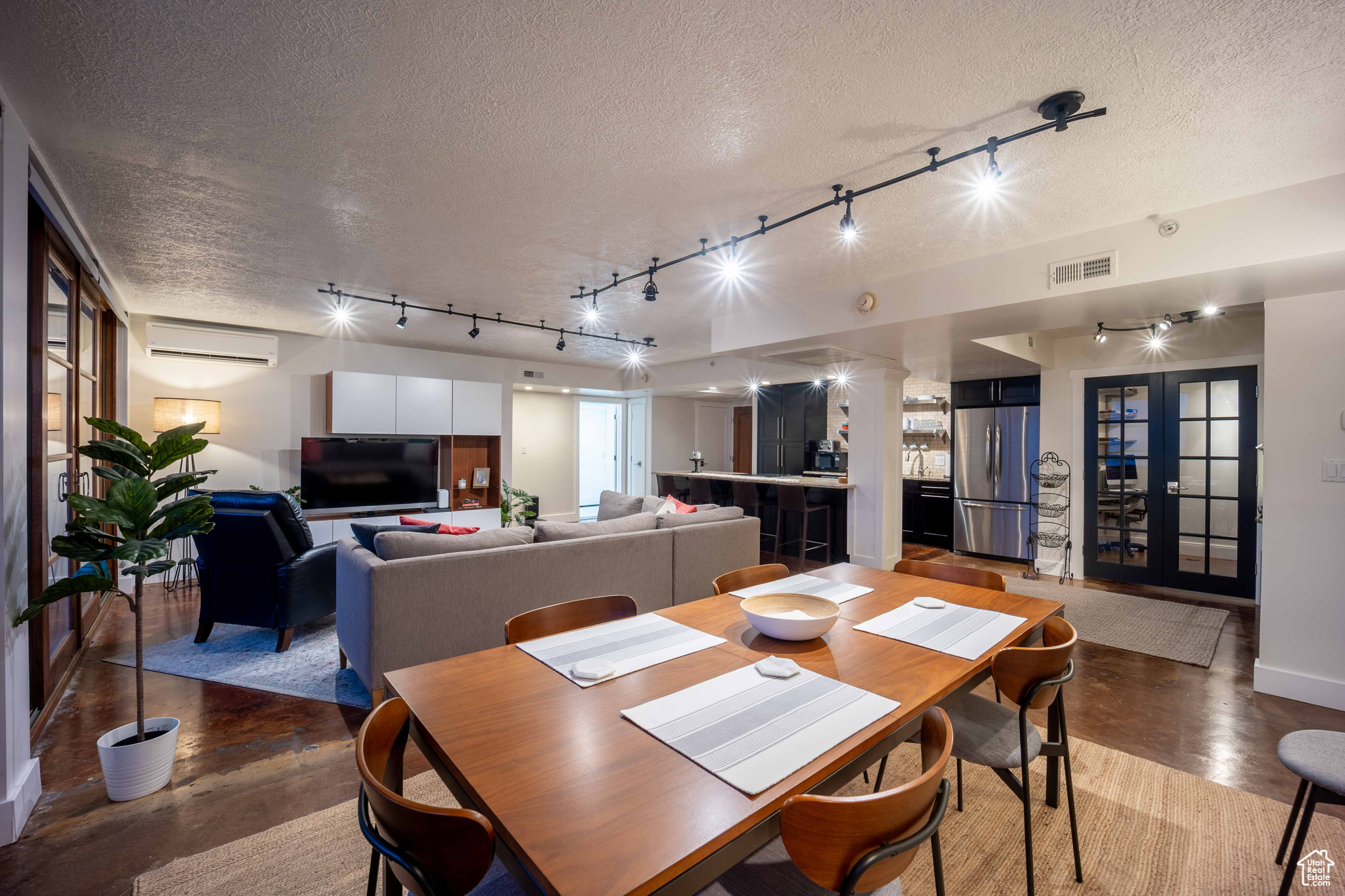 Dining area featuring a textured ceiling, concrete floors, a wall mounted air conditioner, and visible vents