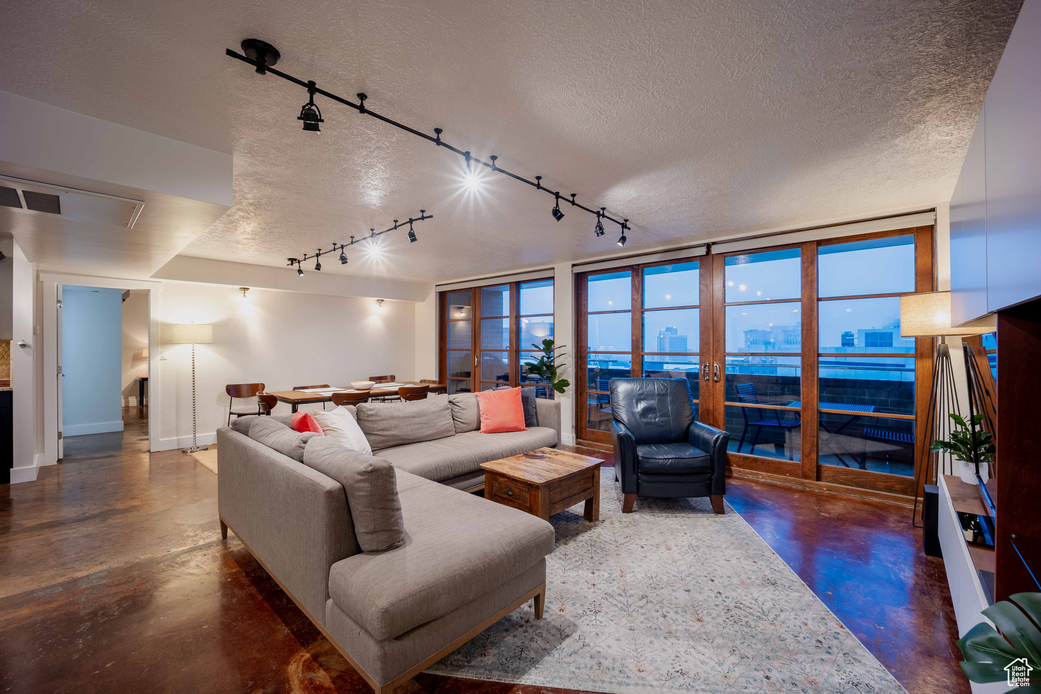 Living room with a view of city, visible vents, concrete flooring, and a textured ceiling
