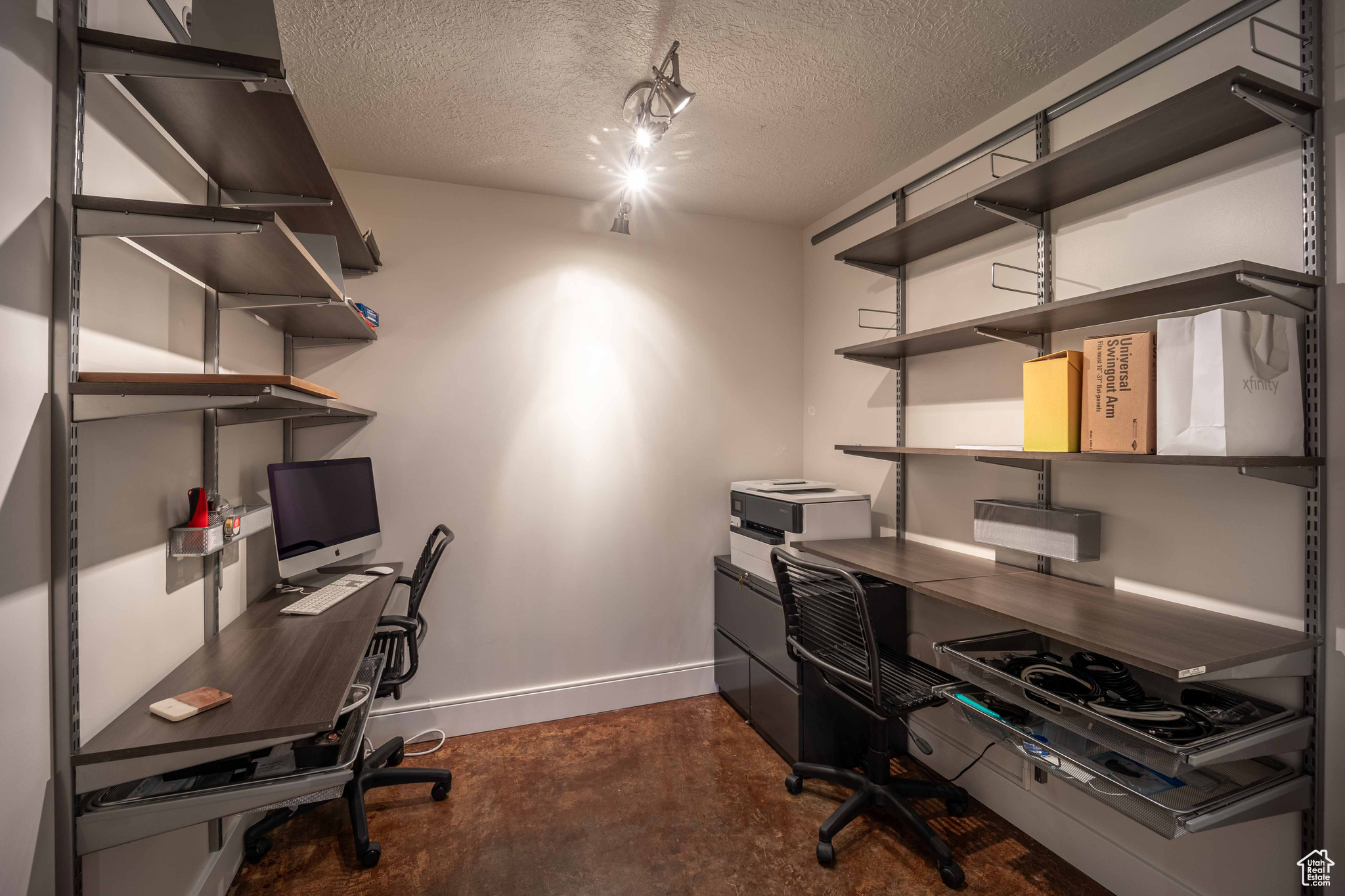 Office area featuring baseboards, concrete flooring, and a textured ceiling