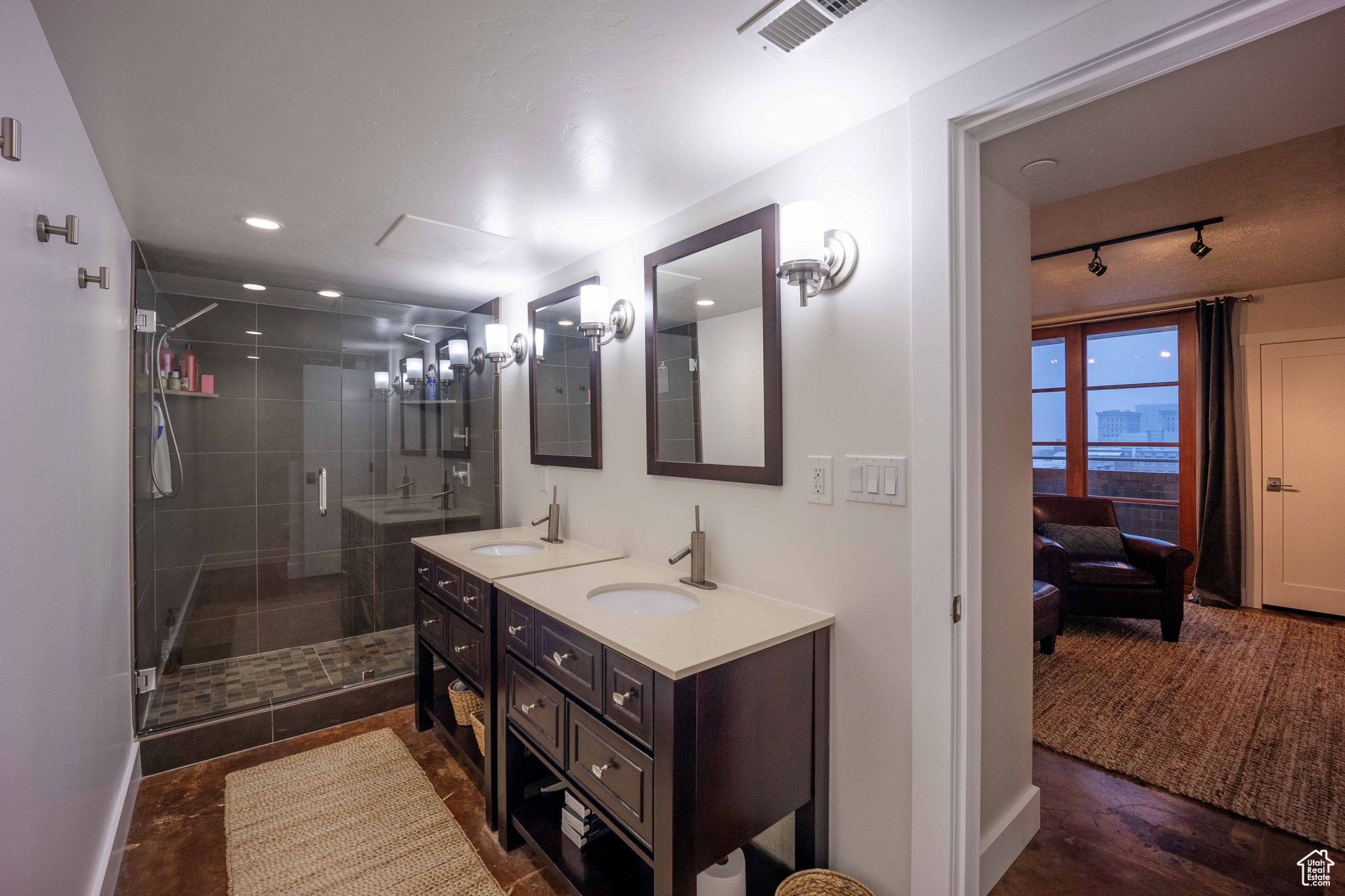Bathroom featuring double vanity, a stall shower, visible vents, and a sink