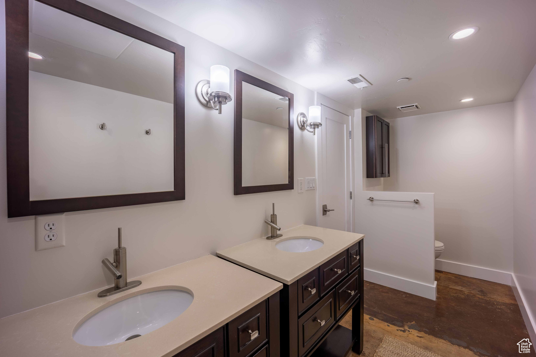 Bathroom with two vanities, a sink, toilet, and baseboards