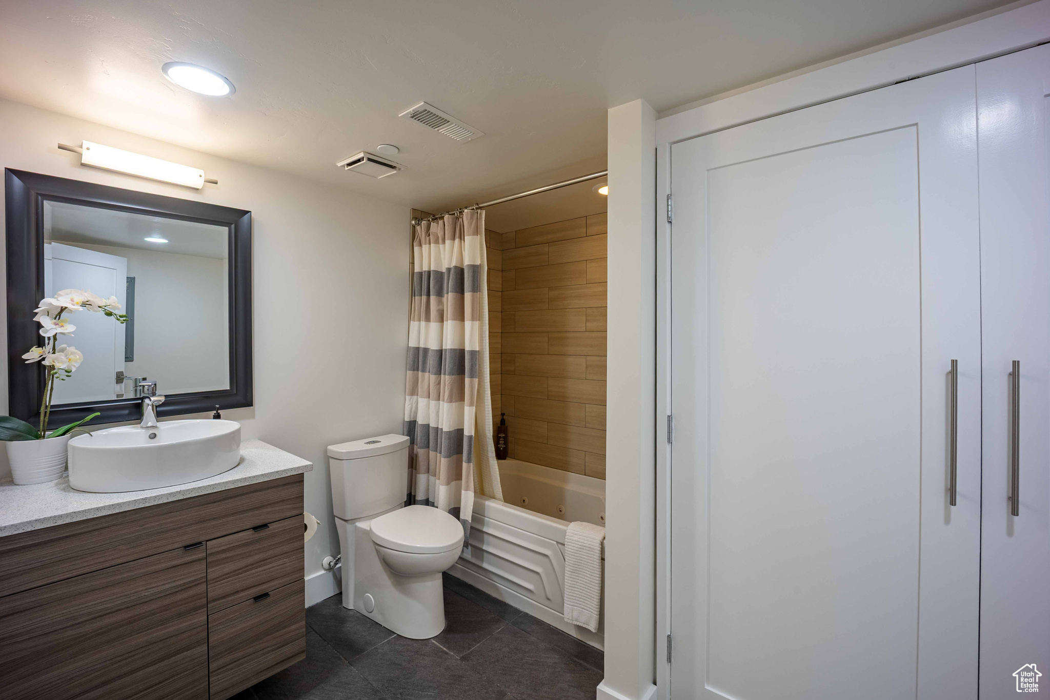 Full bath with visible vents, toilet, tile patterned flooring, shower / bath combo with shower curtain, and vanity
