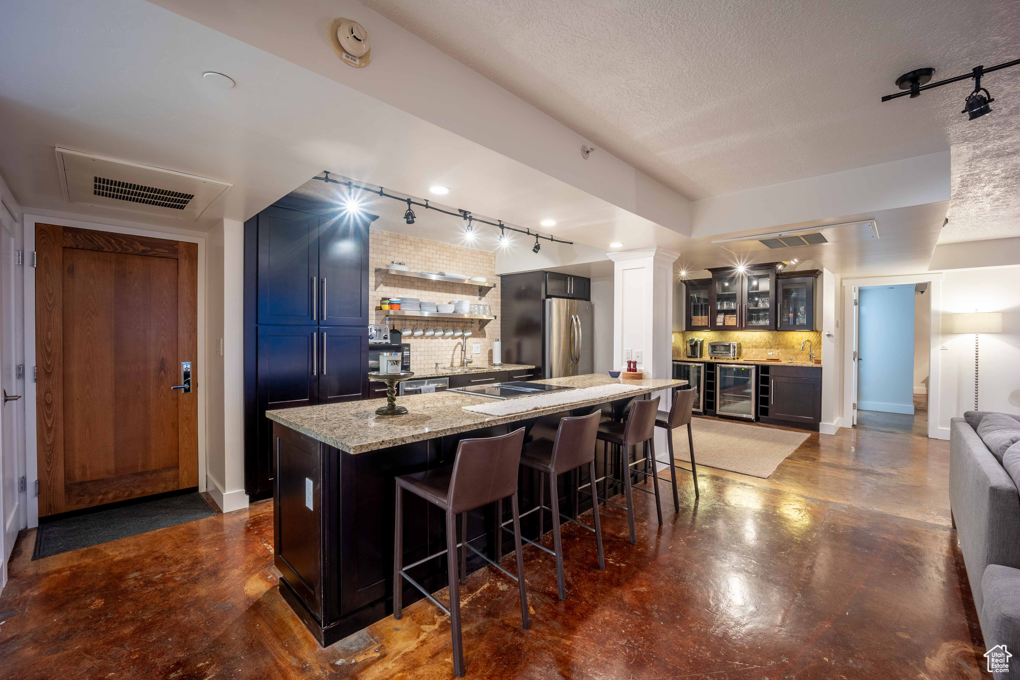 Kitchen with visible vents, decorative backsplash, glass insert cabinets, freestanding refrigerator, and a kitchen island with sink