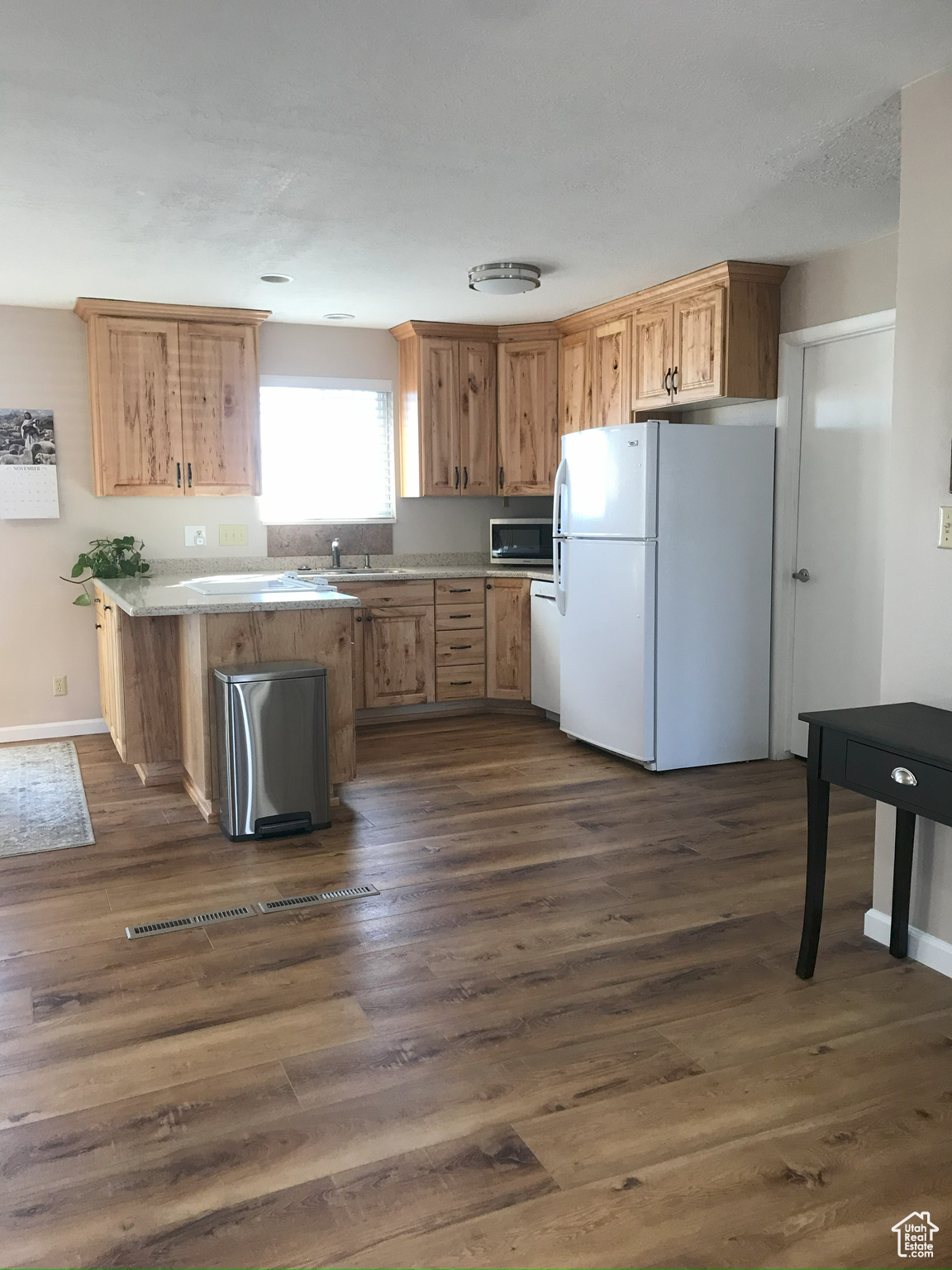 Kitchen featuring light countertops, white appliances, dark wood finished floors, and baseboards
