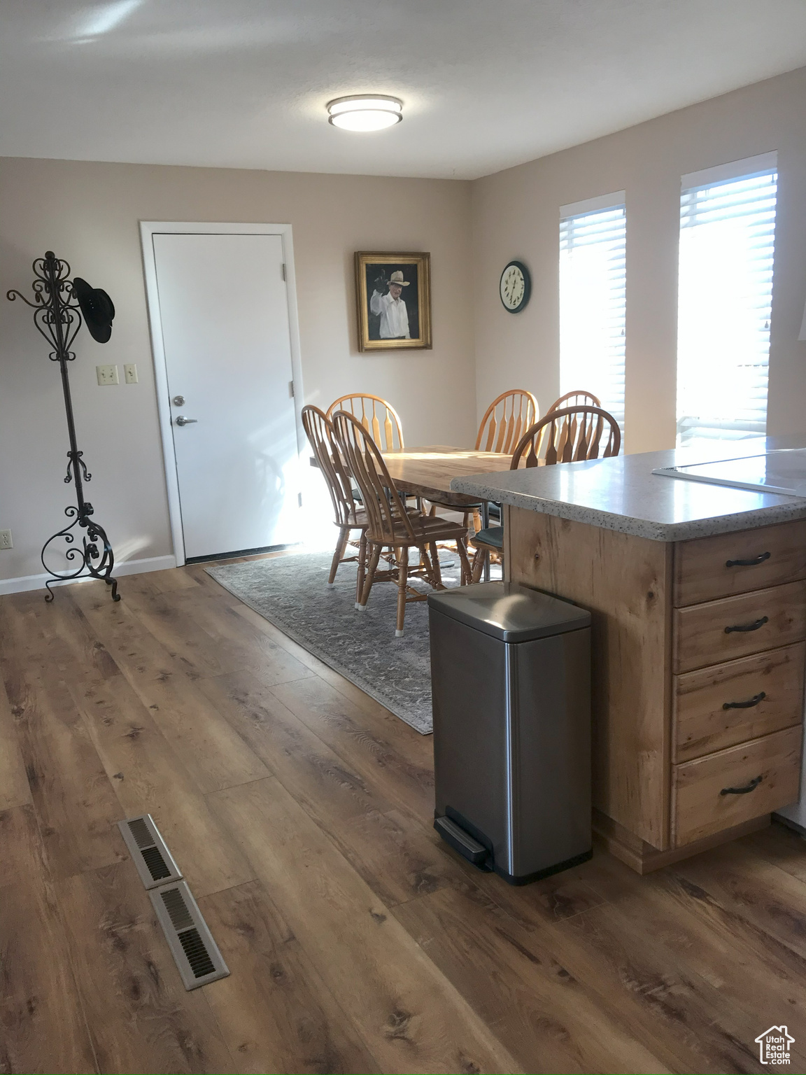 Kitchen with dark wood-type flooring, brown cabinetry, and baseboards