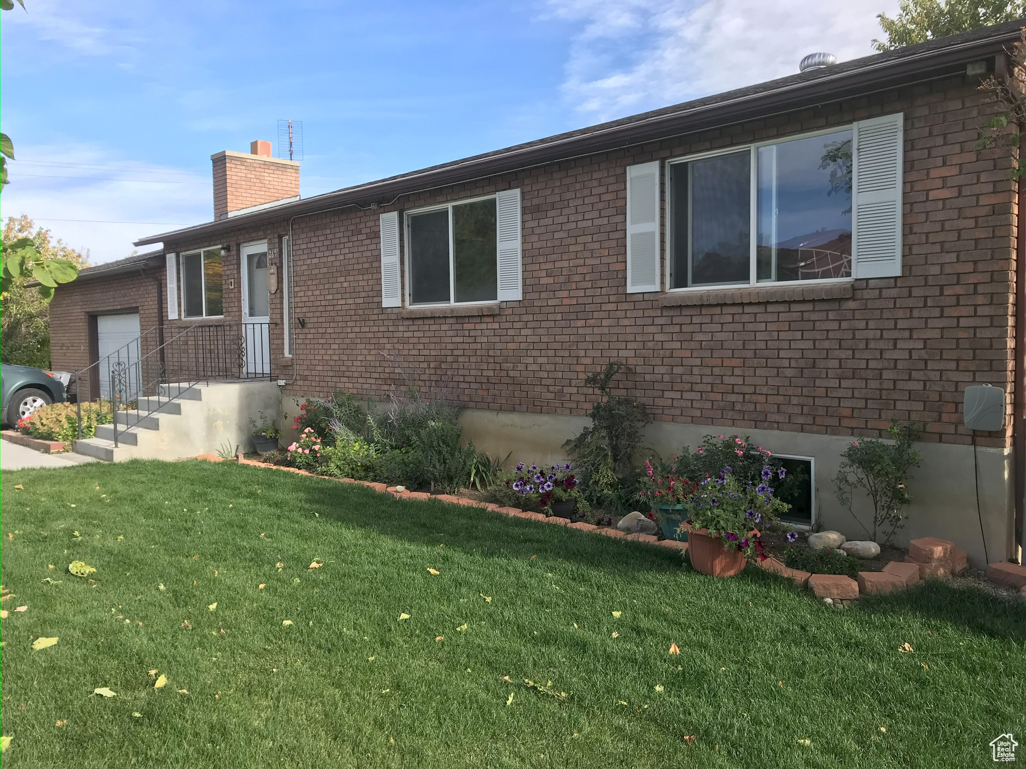 Single story home featuring a front lawn, a chimney, and brick siding