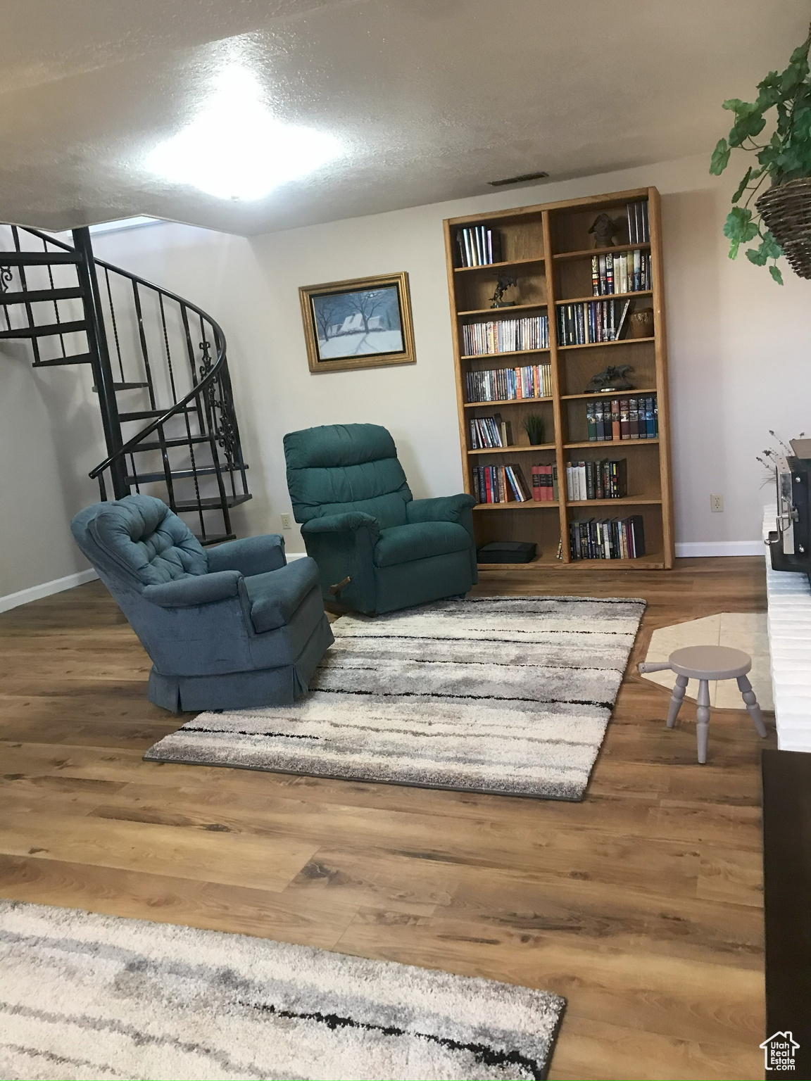 Living area with wood finished floors, a textured ceiling, baseboards, and stairs