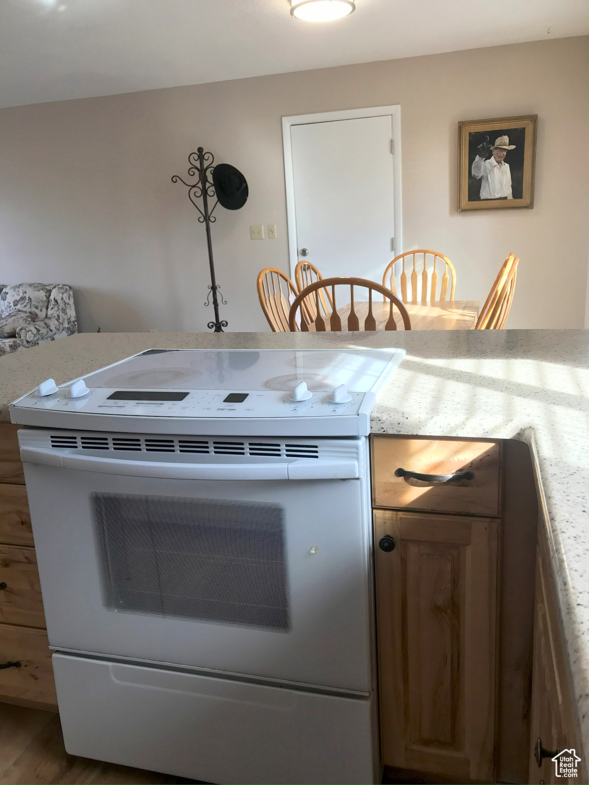 Kitchen with white electric stove, light stone counters, and wood finished floors