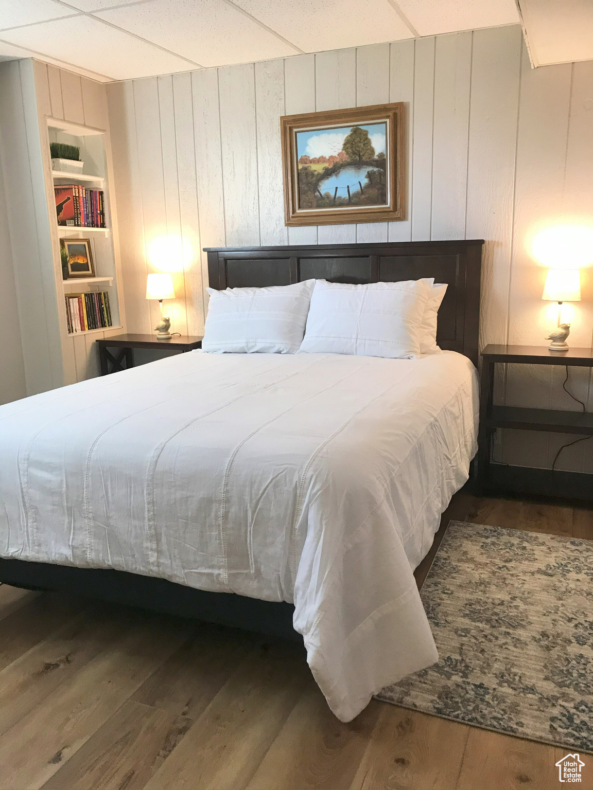 Bedroom with wooden walls and dark wood-type flooring
